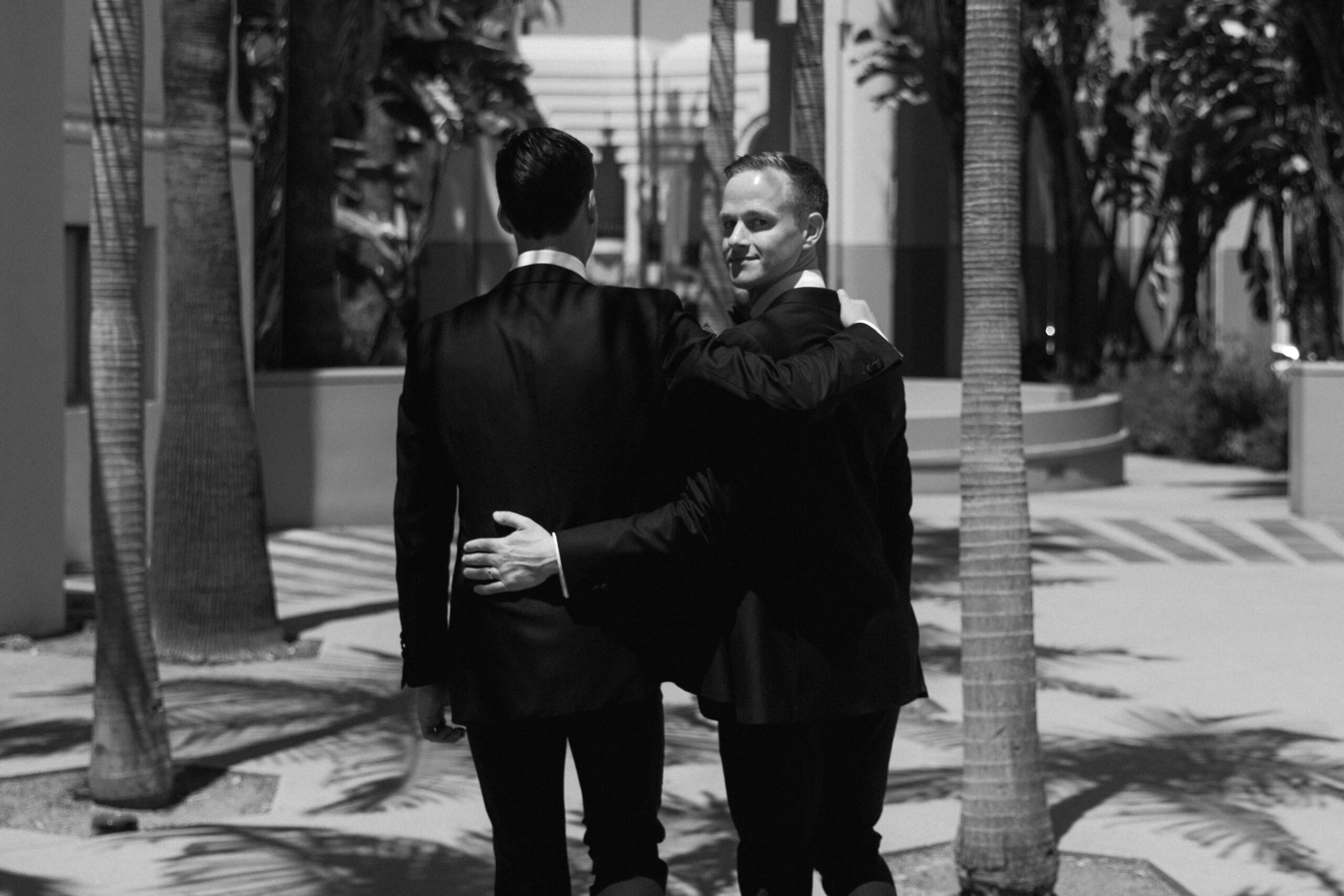black and white photo of gay couple with arms around each other walking through courtyard at Beverly Hills City Hall