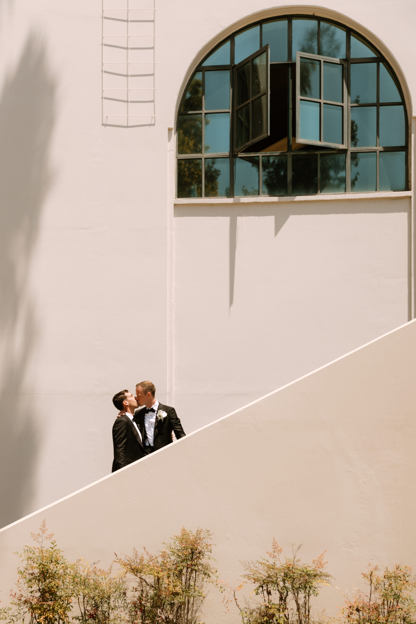gay couple leans in for kiss on staircase at Beverly Hills City Hall