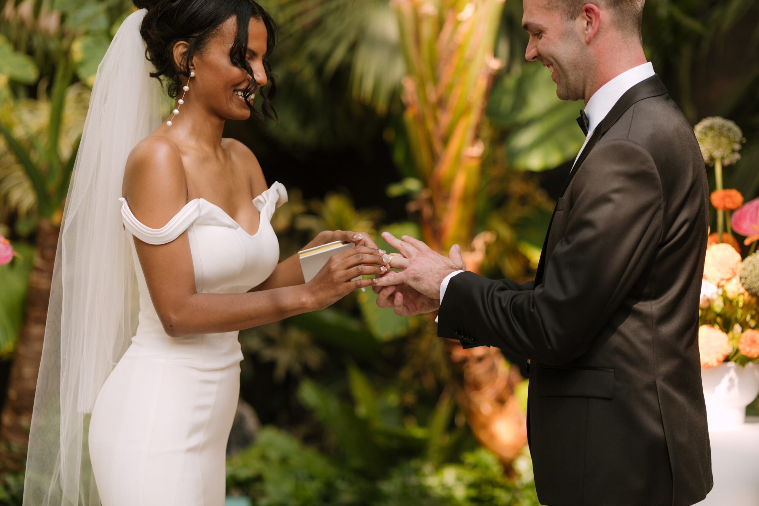 Black bride and white groom exchanging rings in tropical ceremony space at Grass Room DTLA