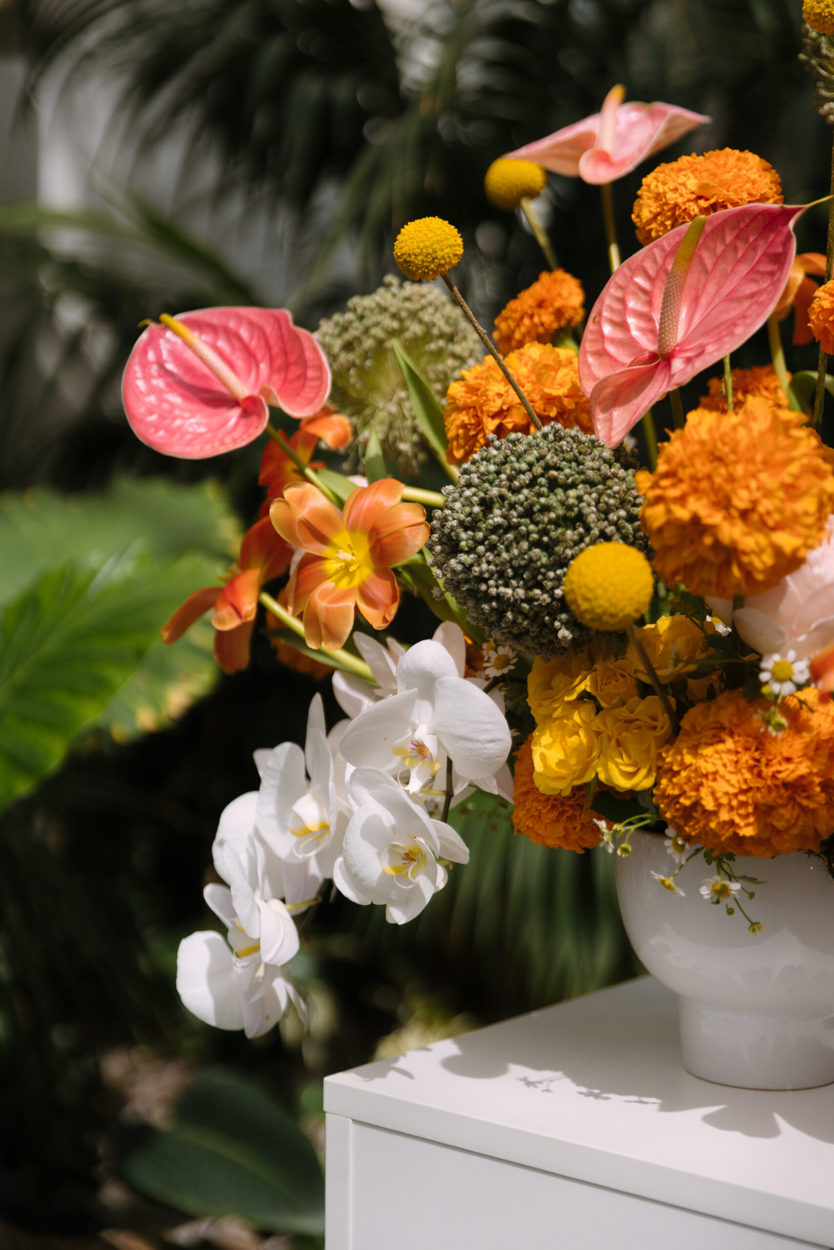 closeup of red, orange, and yellow tropical floral arrangement and white orchids for wedding ceremony space