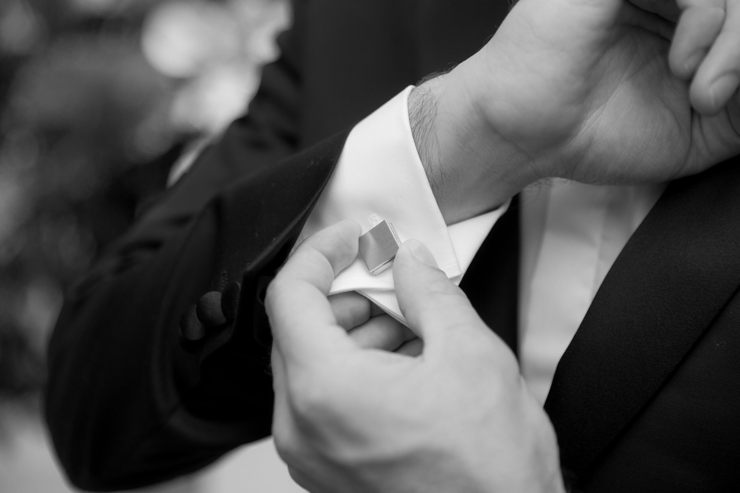 black and white close up of groom adjusting his cufflinks