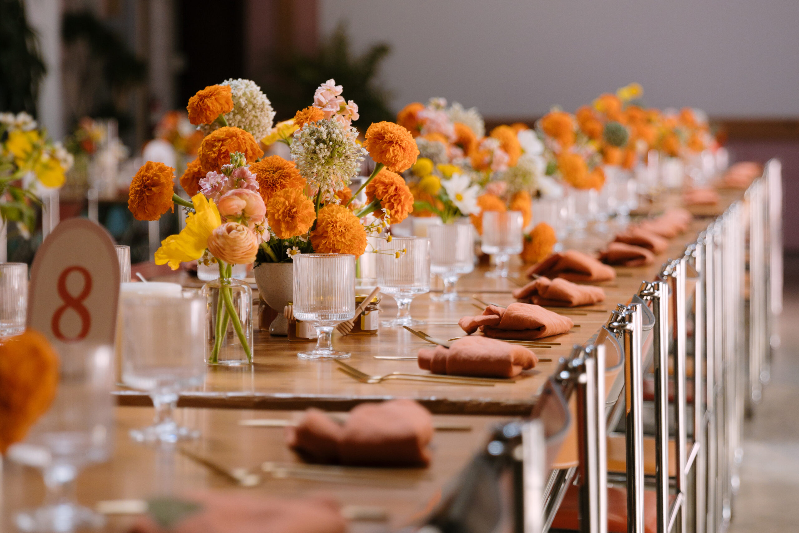 tropical tablescape with pink, yellow, and orange flowers and fluted water goblets