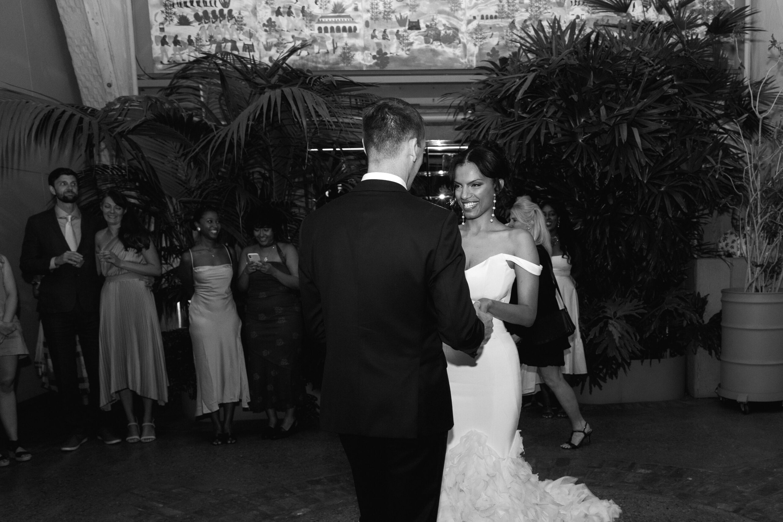 direct flash black and white wide photo of bride and groom sharing their first dance