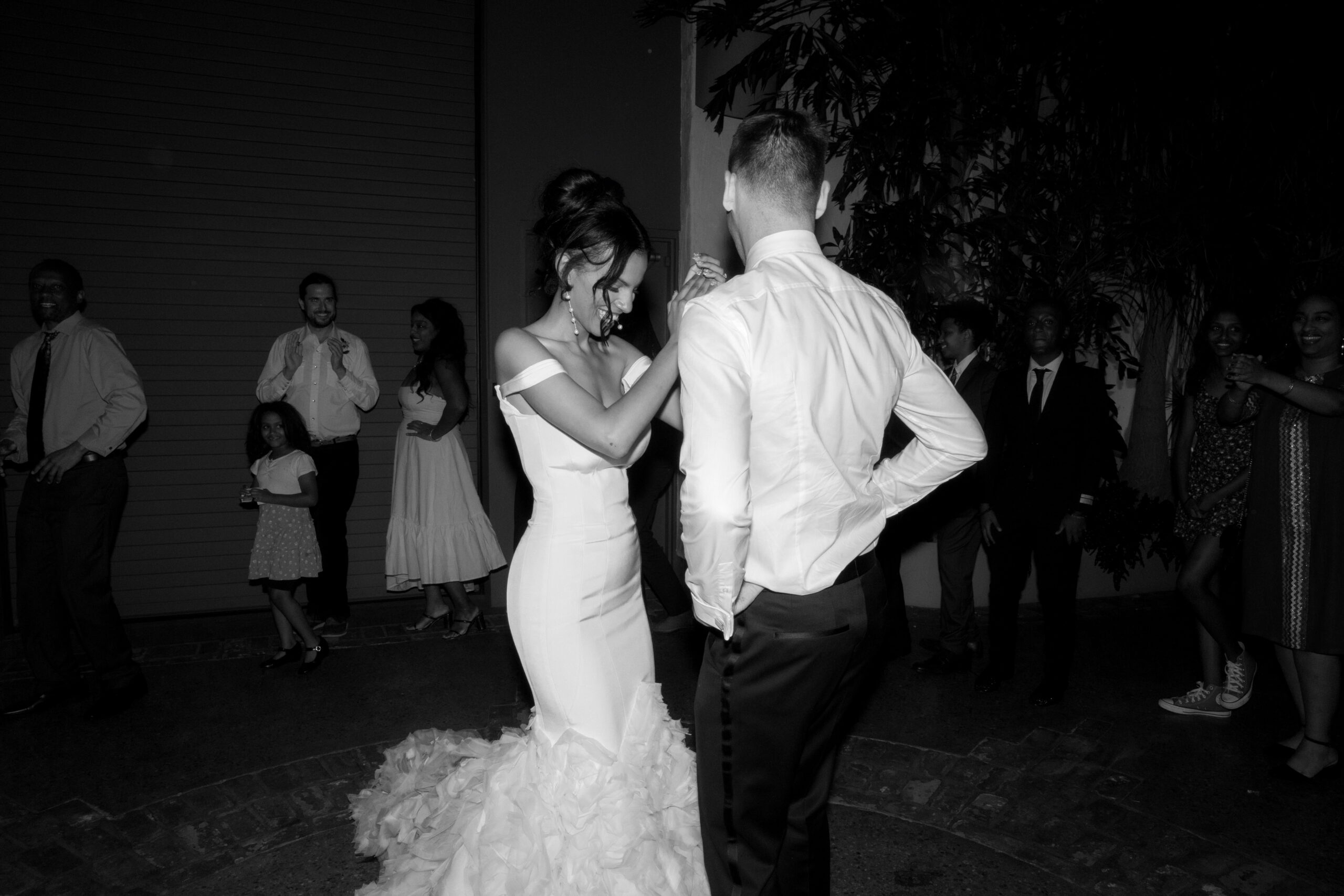 black and white direct flash photo of bride and groom with guests dancing an Eskista at Grass Room DTLA