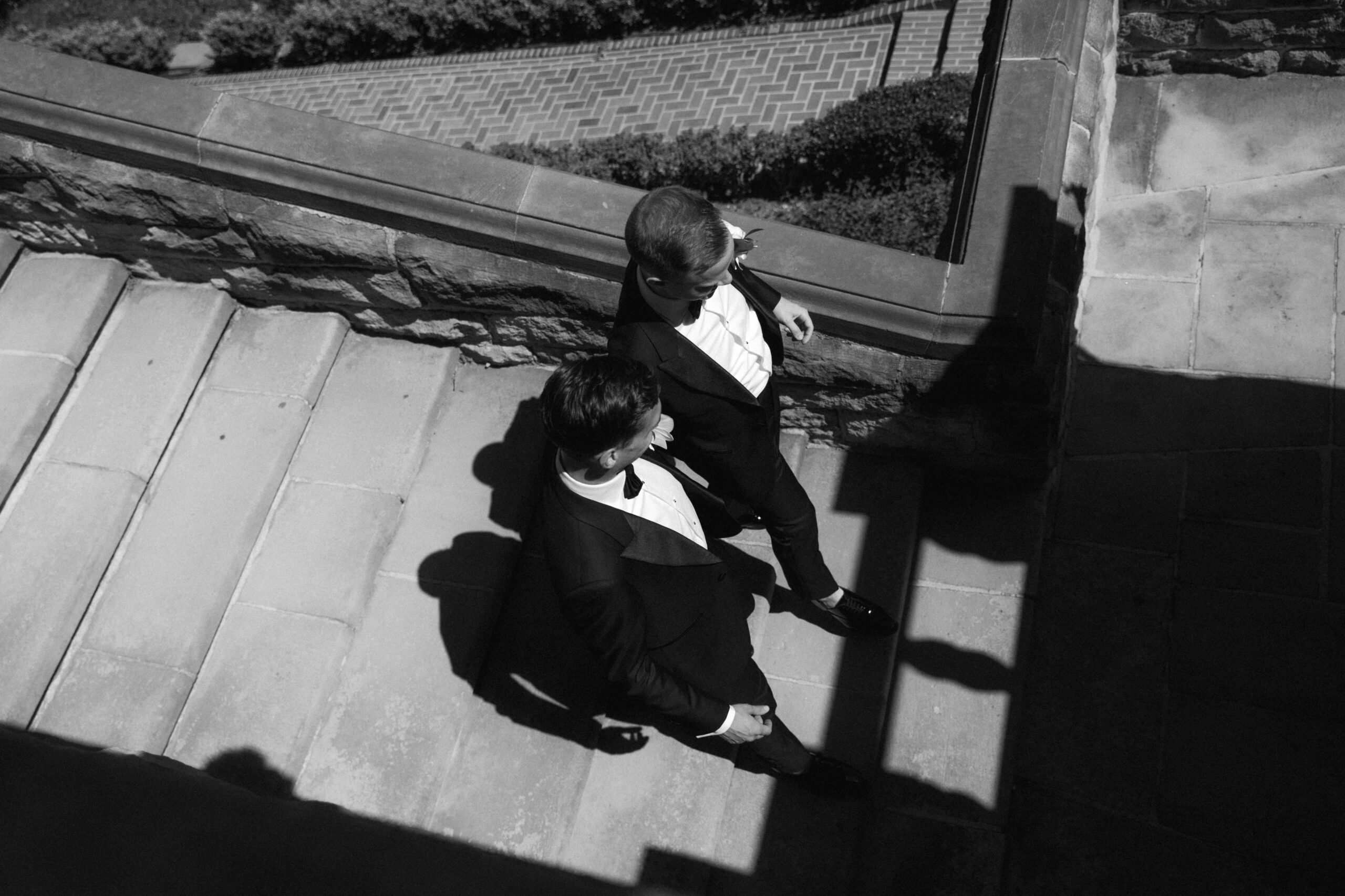 black and white photo looking down at gay couple descending terrace stairs at Greystone Mansion