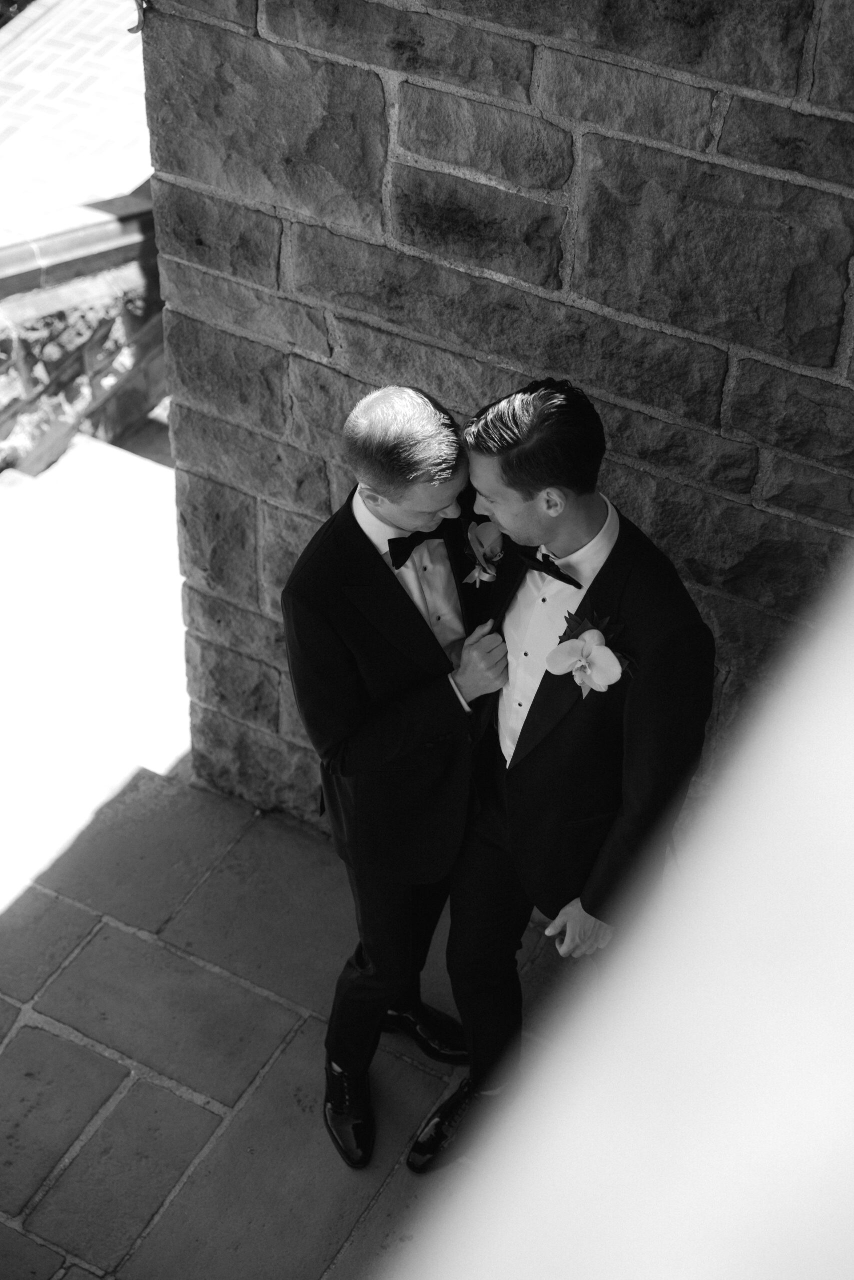 black and white photo of couple leaning in for embrace at the bottom of stairwell at Greystone Mansion