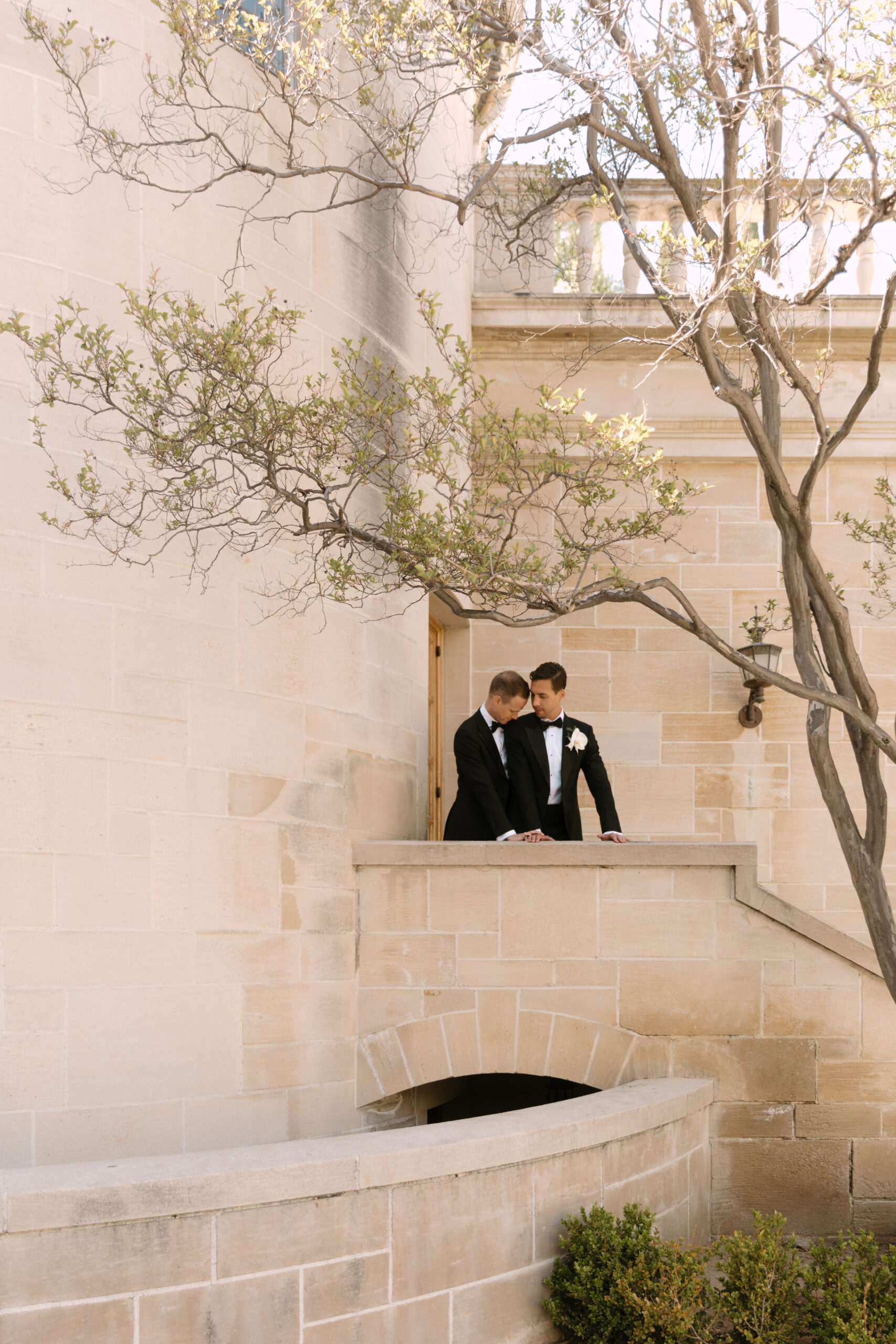 gay couple overlooking stairway and balcony in courtyard at Greystone Mansion