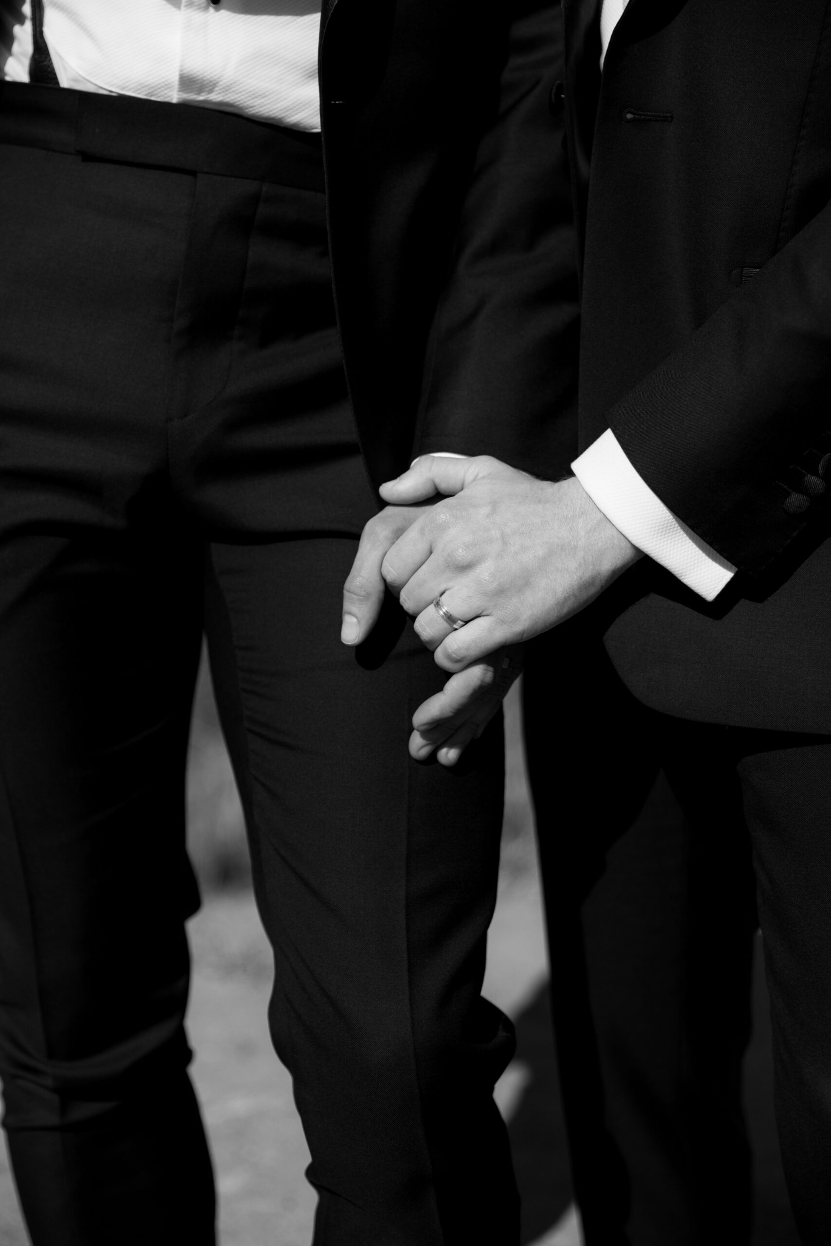 black and white closeup of gay couples hands showing their wedding bands