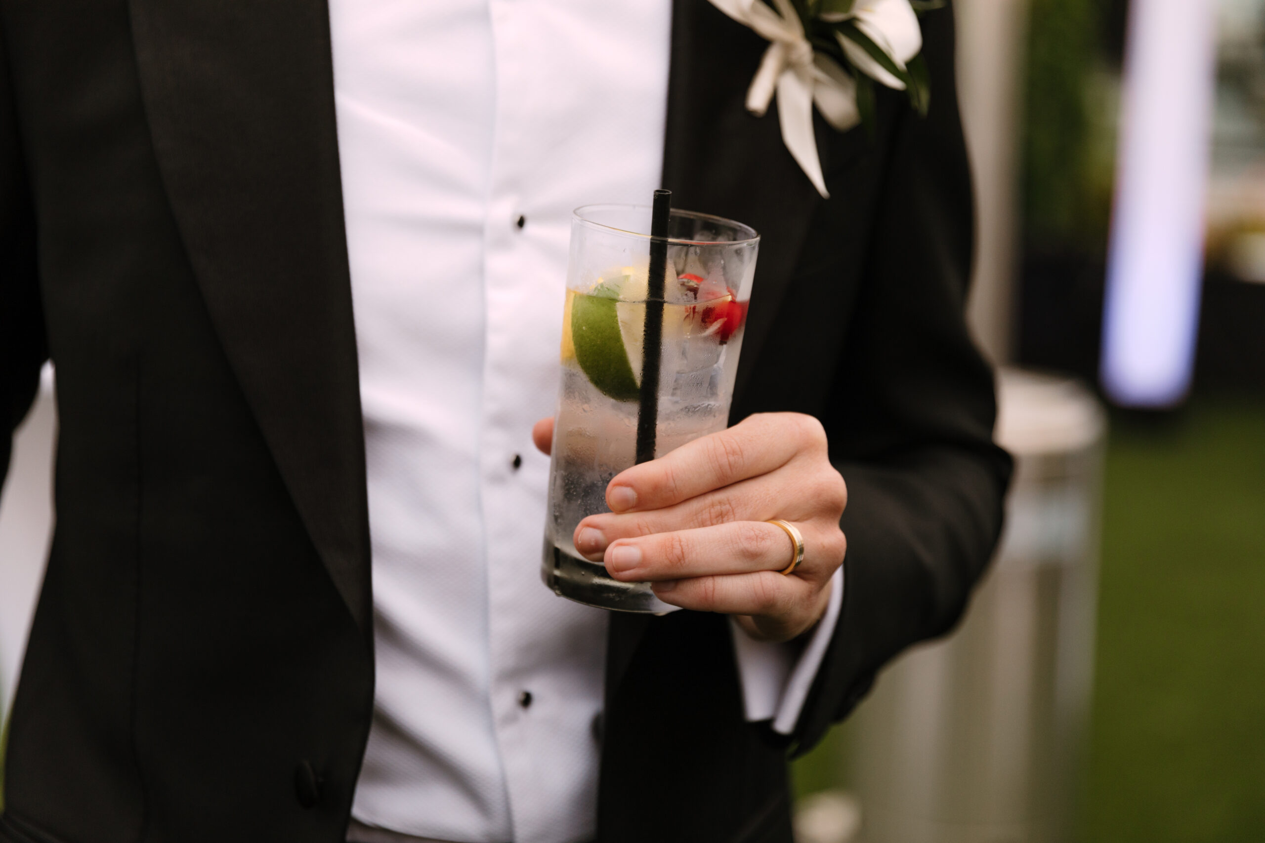 close up of wedding guest holding highball glass with clear cocktail