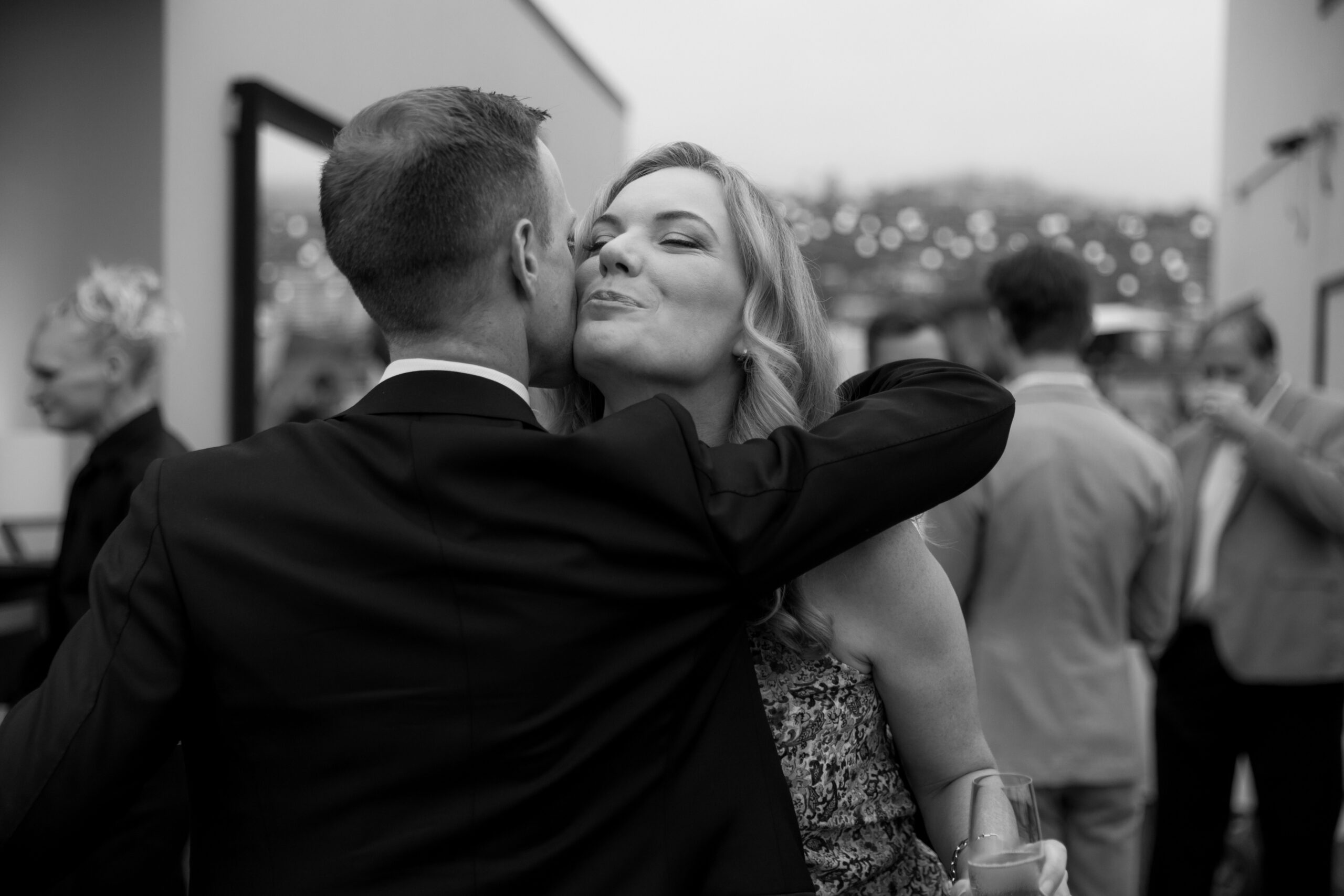 black and white photo of guest embracing groom on rooftop at Kimpton La Peer Hotel