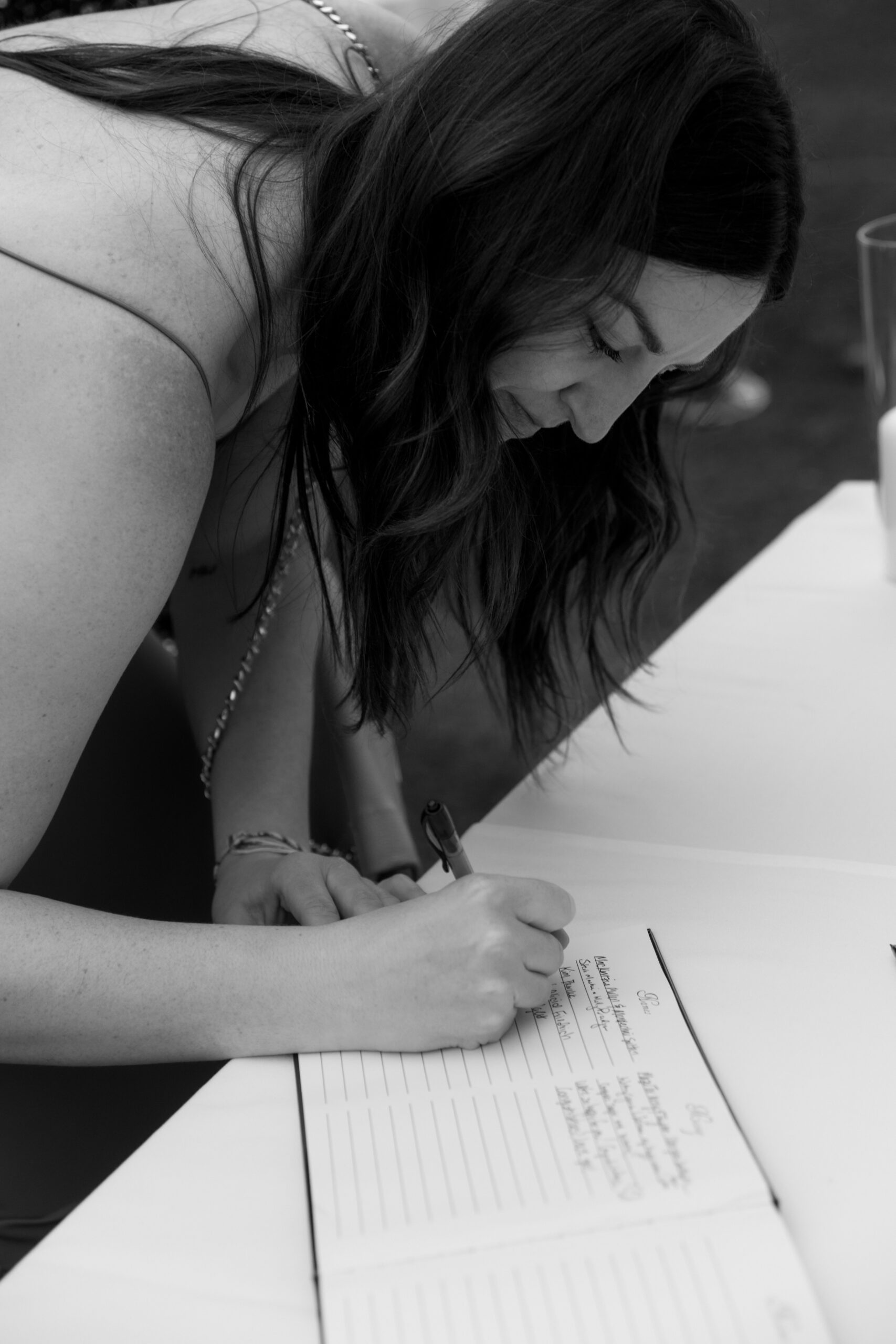 black and white photo of woman signing guestbook