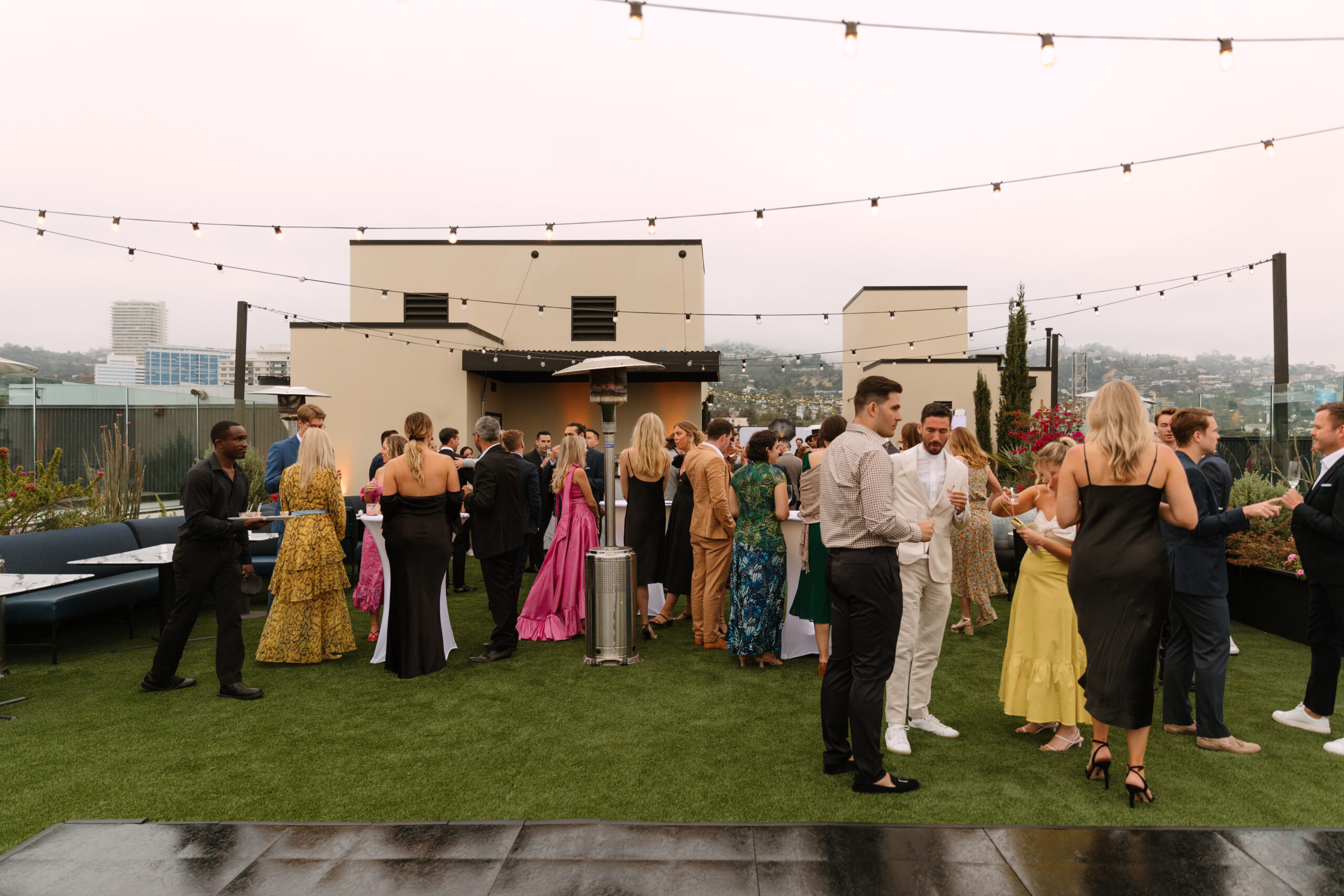wide shot of guests mingling on rooftop during wedding cocktail hour at Kimpton La Peer Hotel