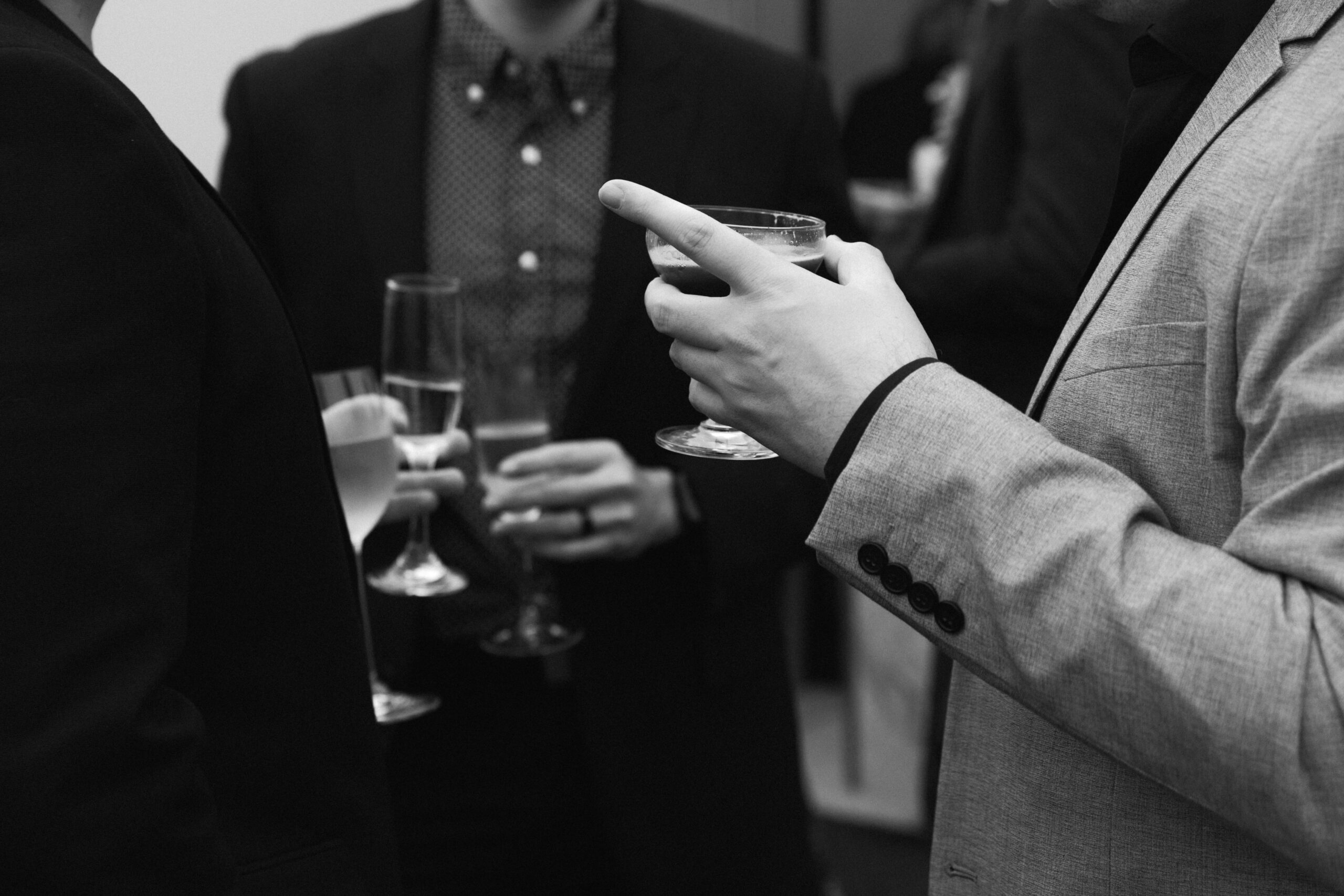 black and white closeup of wedding guests holding champagne and espresso martinis