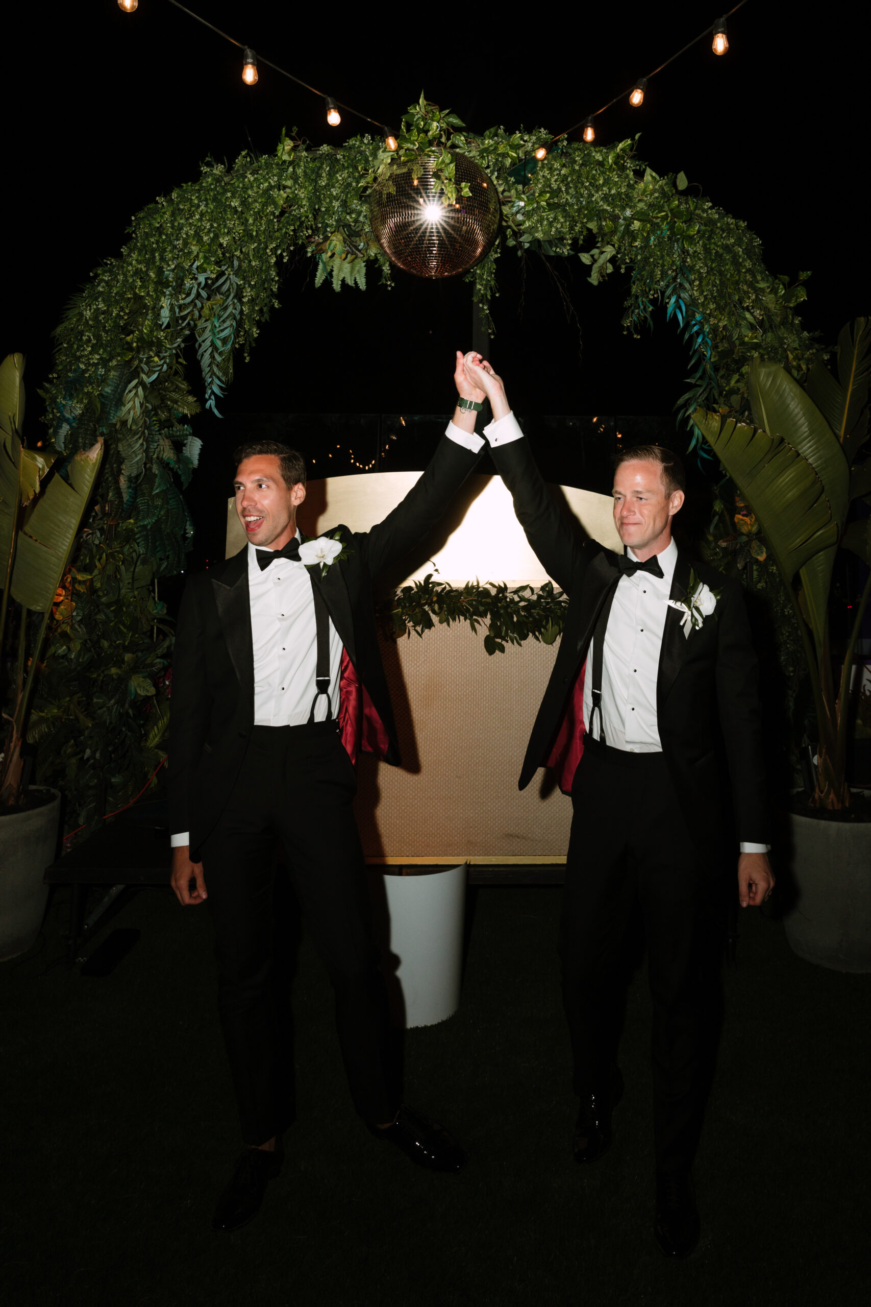direct flash photo on Kimpton La Peer rooftop of gay grooms raising their hands in the air after their first kiss
