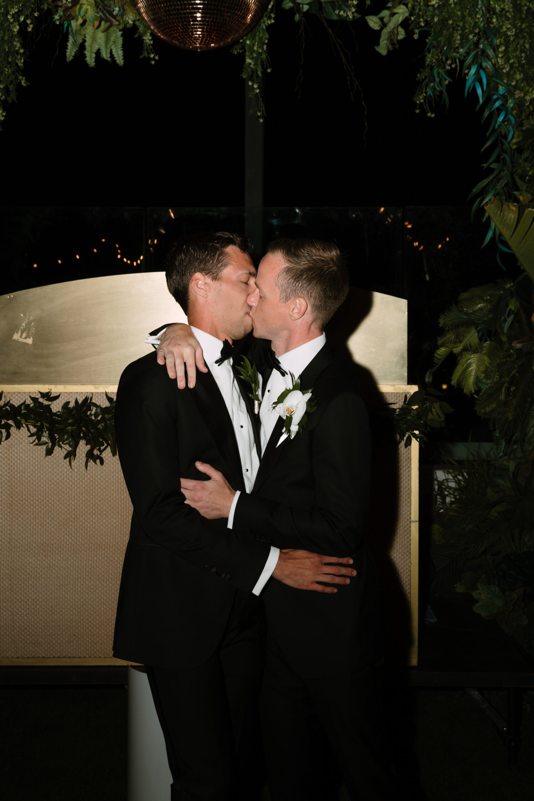 direct flash photo on Kimpton La Peer rooftop of gay grooms sharing their first kiss