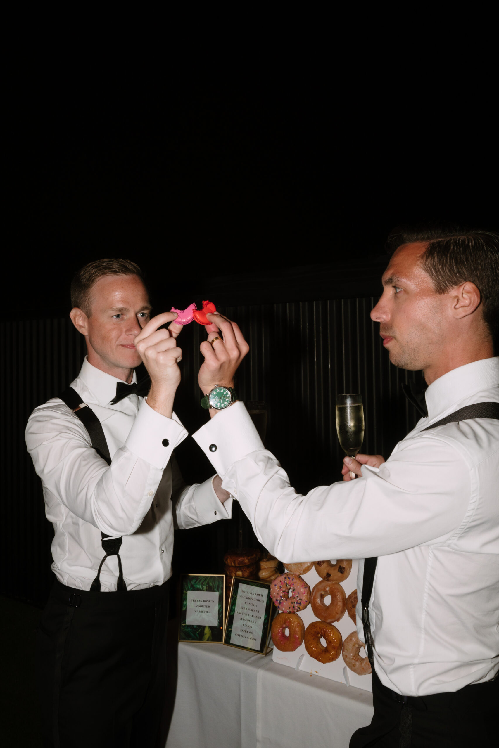 direct flash photo of gay grooms toasting with colorful macarons