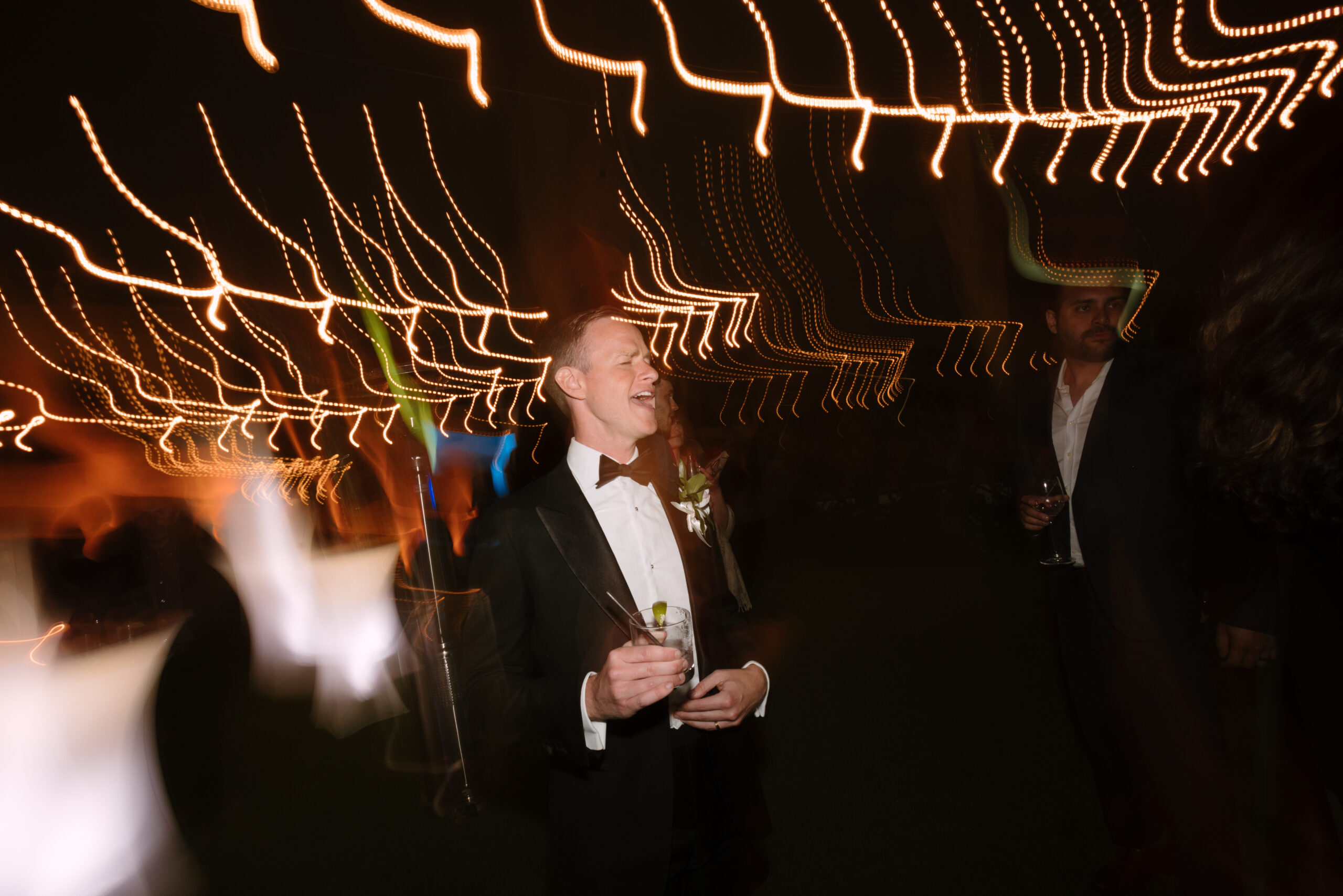 shutter drag photo of groom singing along to music on the dancefloor
