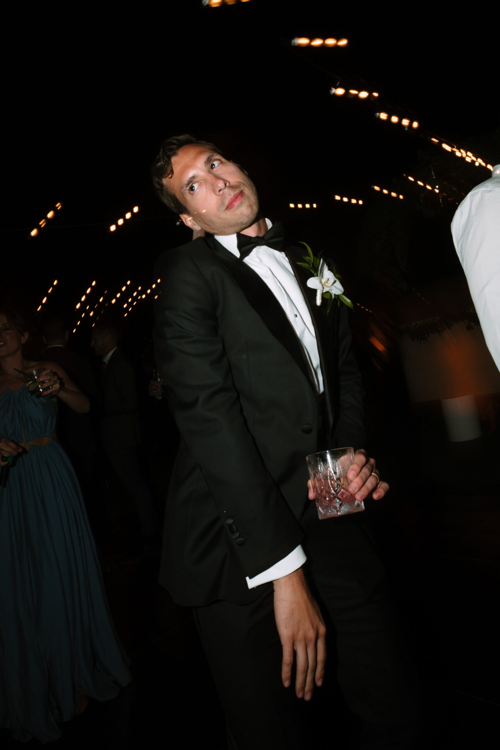 shutter drag photo of groom dancing with a cocktail in his hand