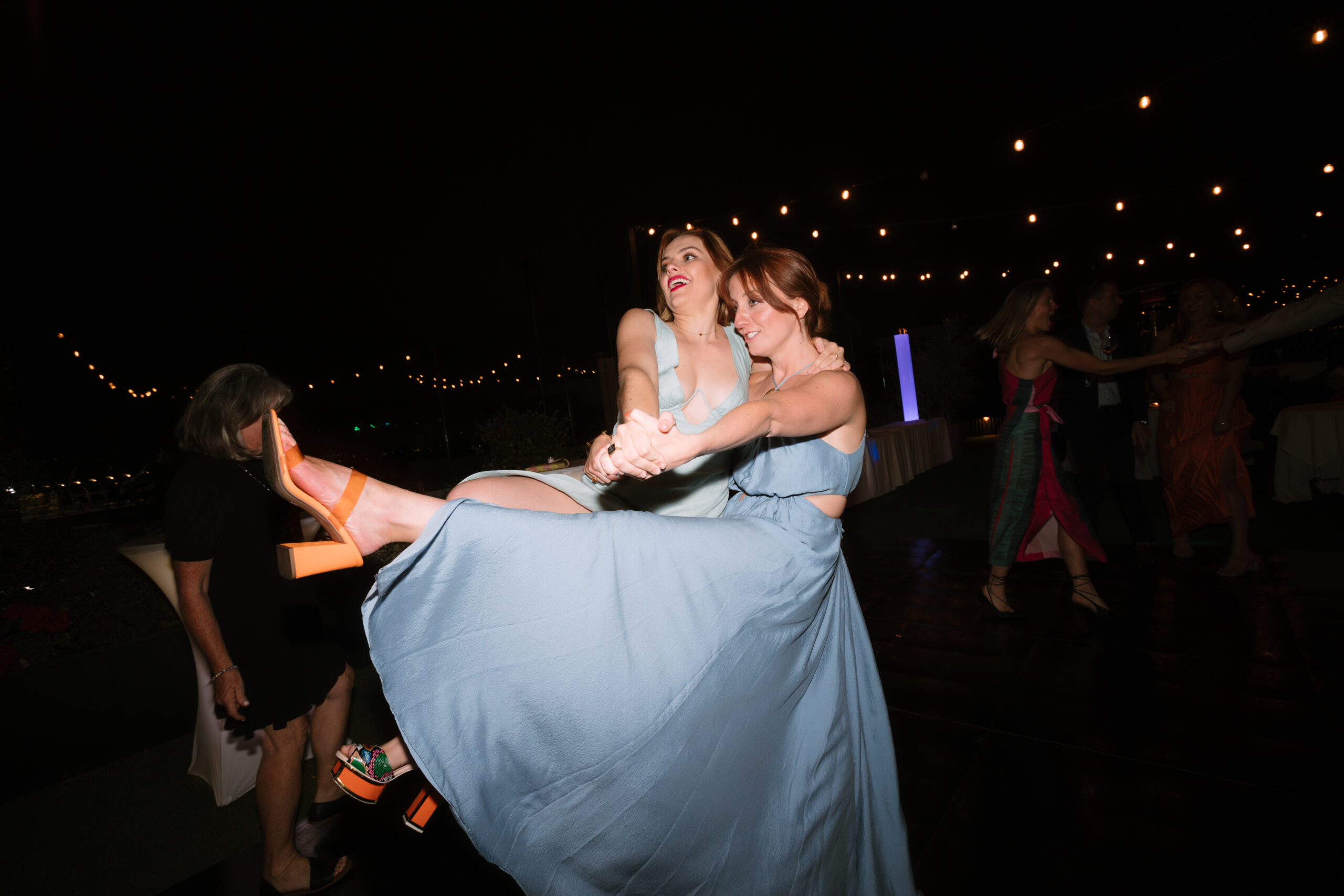 direct flash photo of wedding guests dancing and kicking their heels in the air