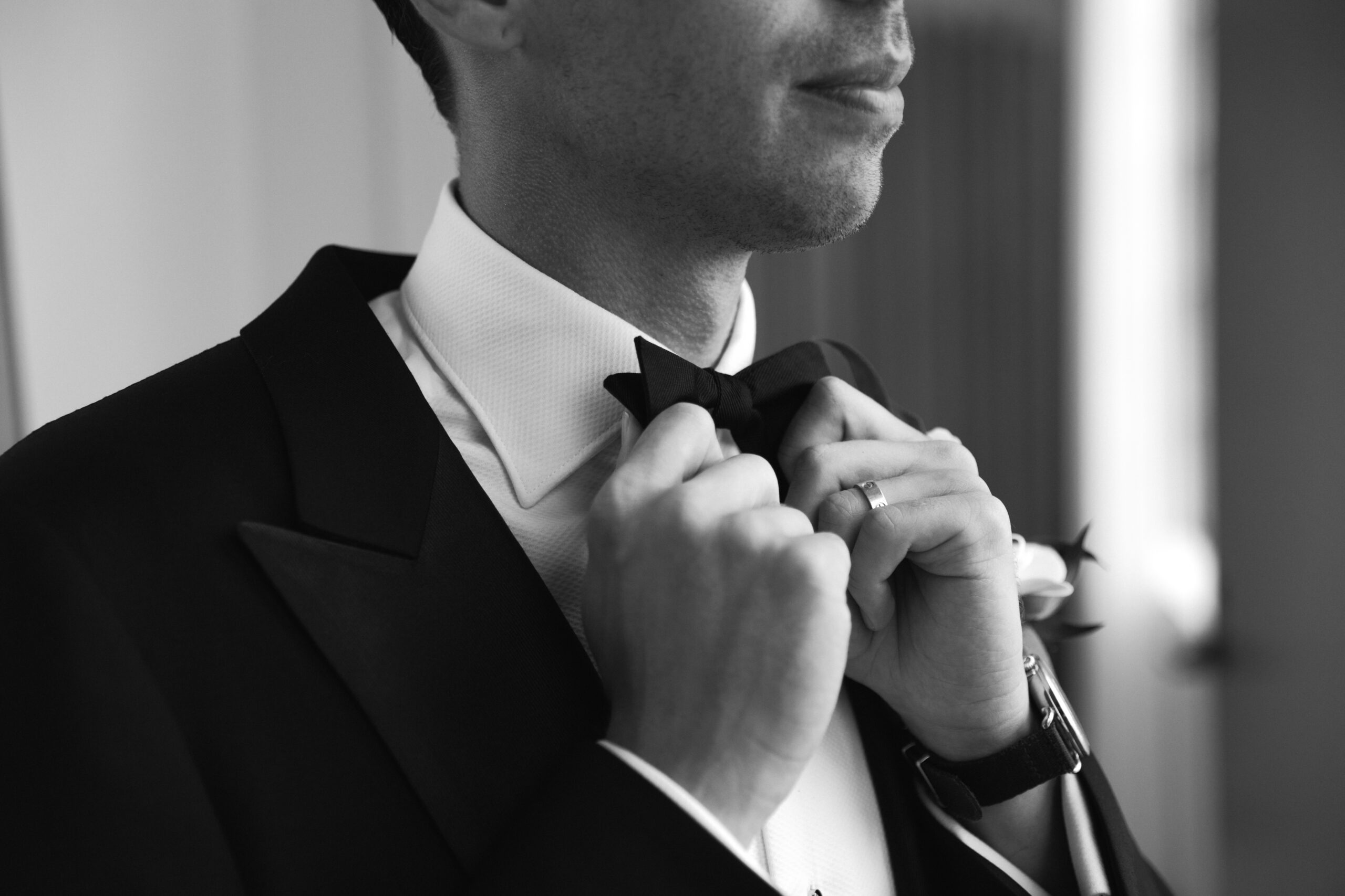 black and white closeup of groom adjusting his bowtie