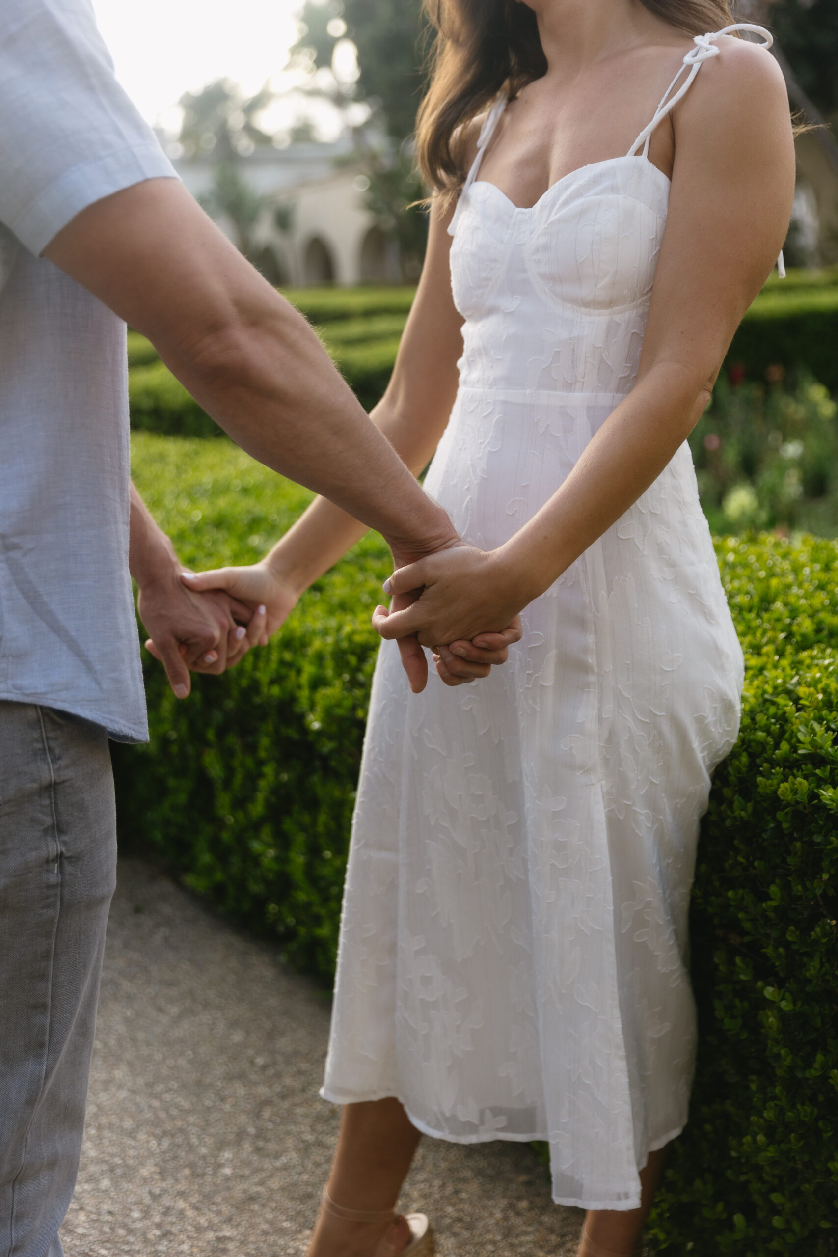 cropped photo of couple holding hands in Alcazar Garden at Balboa Park