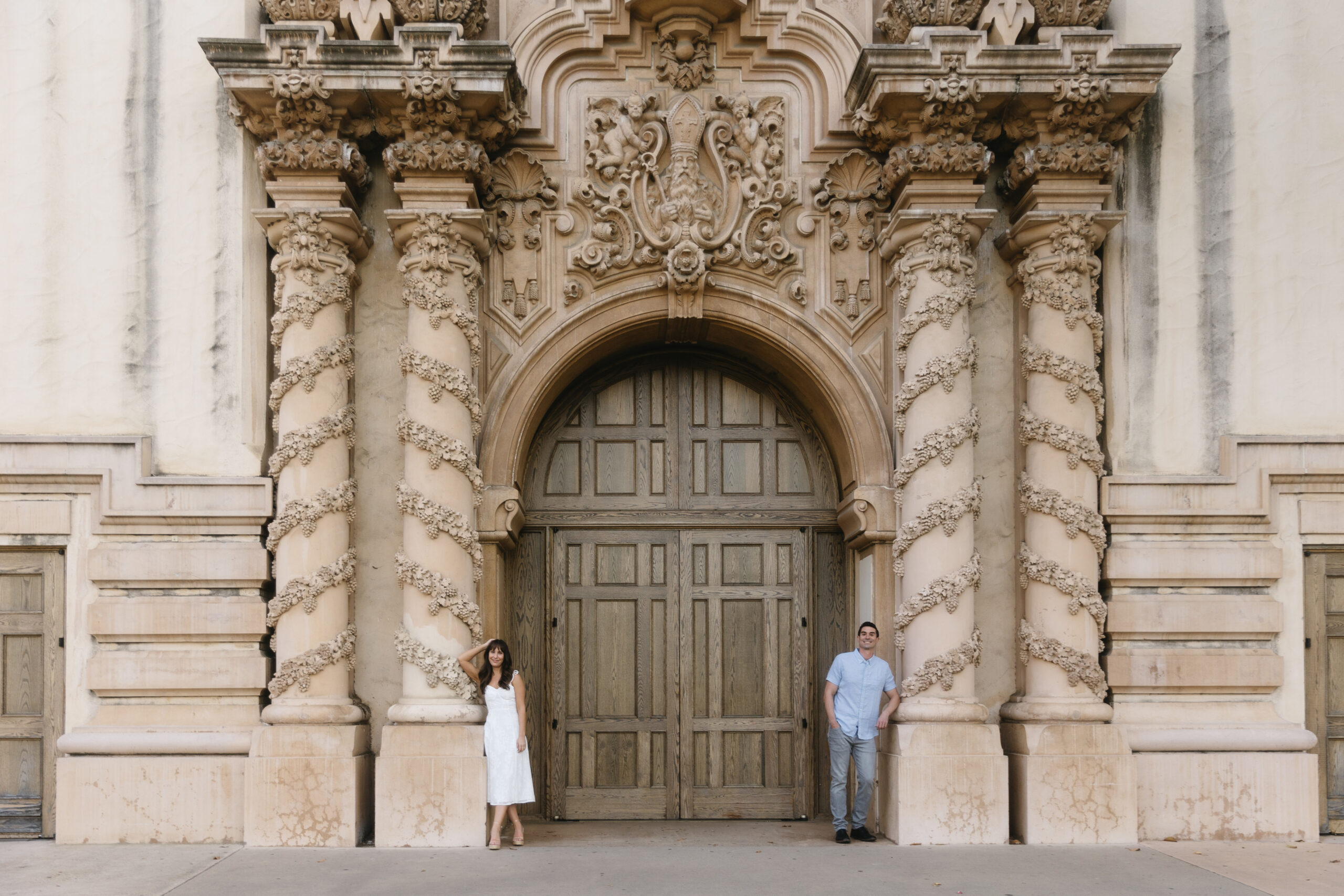 couple leaning against ornate carved pillars of Casa del Prado at Balboa Park