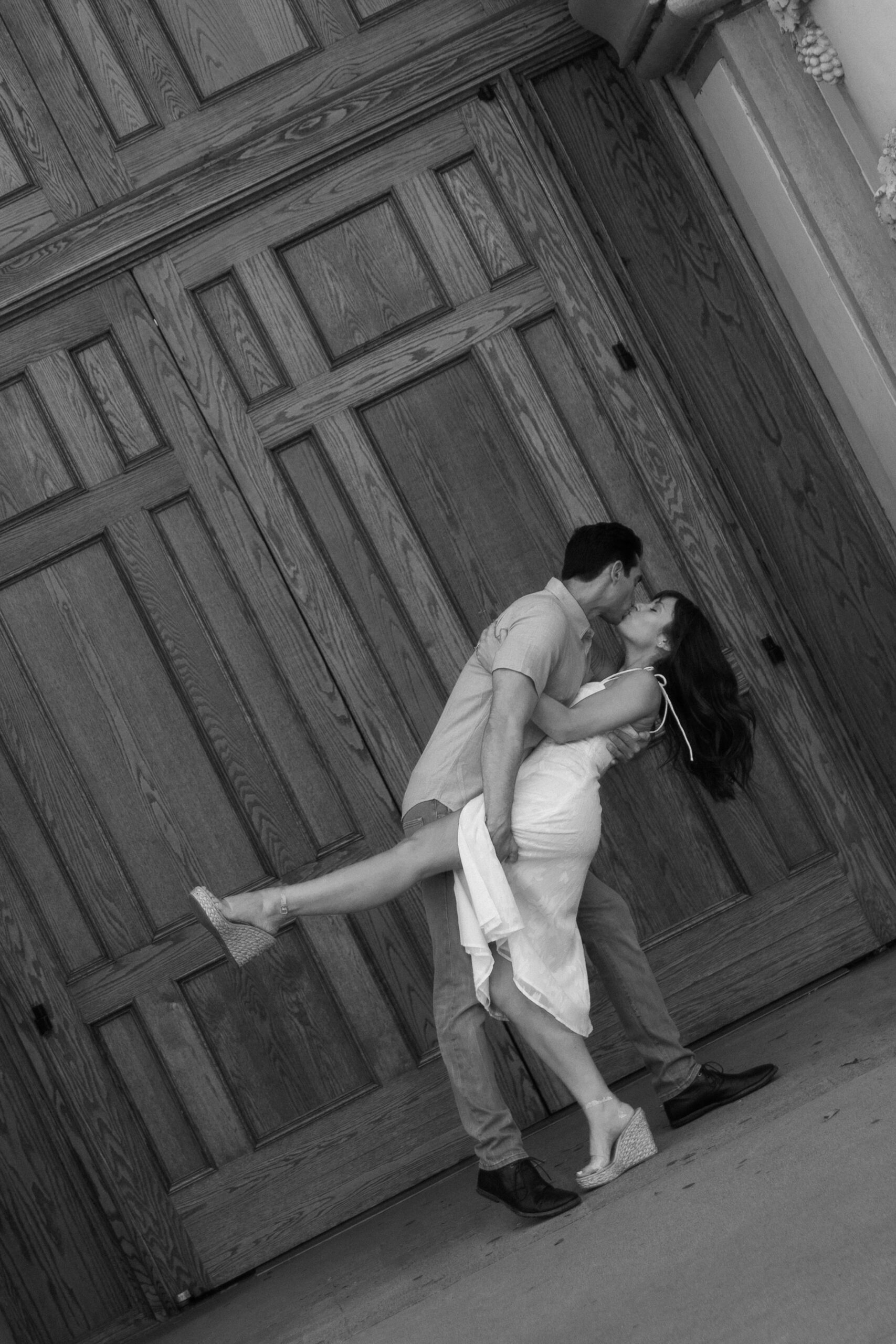 black and white photo of couple dip kissing in front of Casa del Prado in Balboa Park