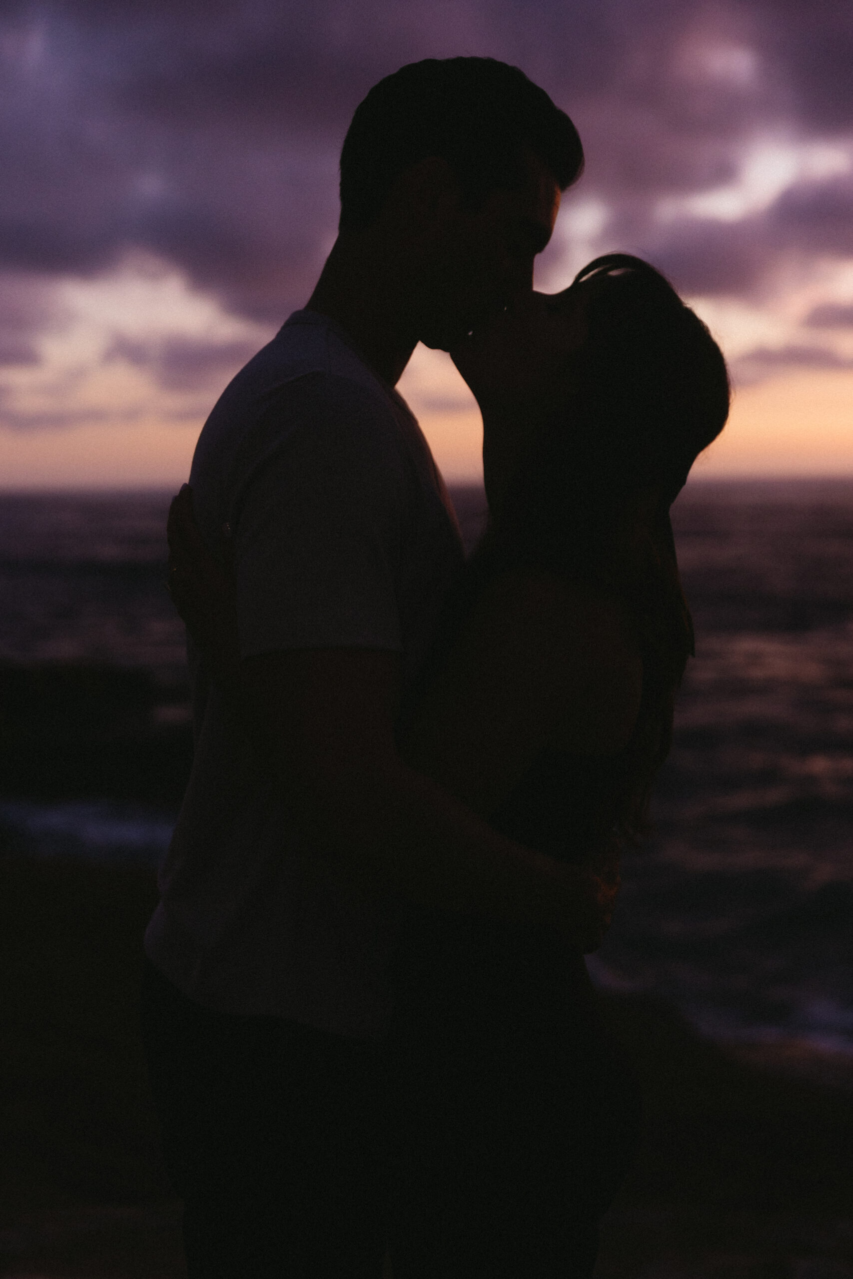 silhouette of couple kissing in front of a purple skyline at Sunset Cliffs
