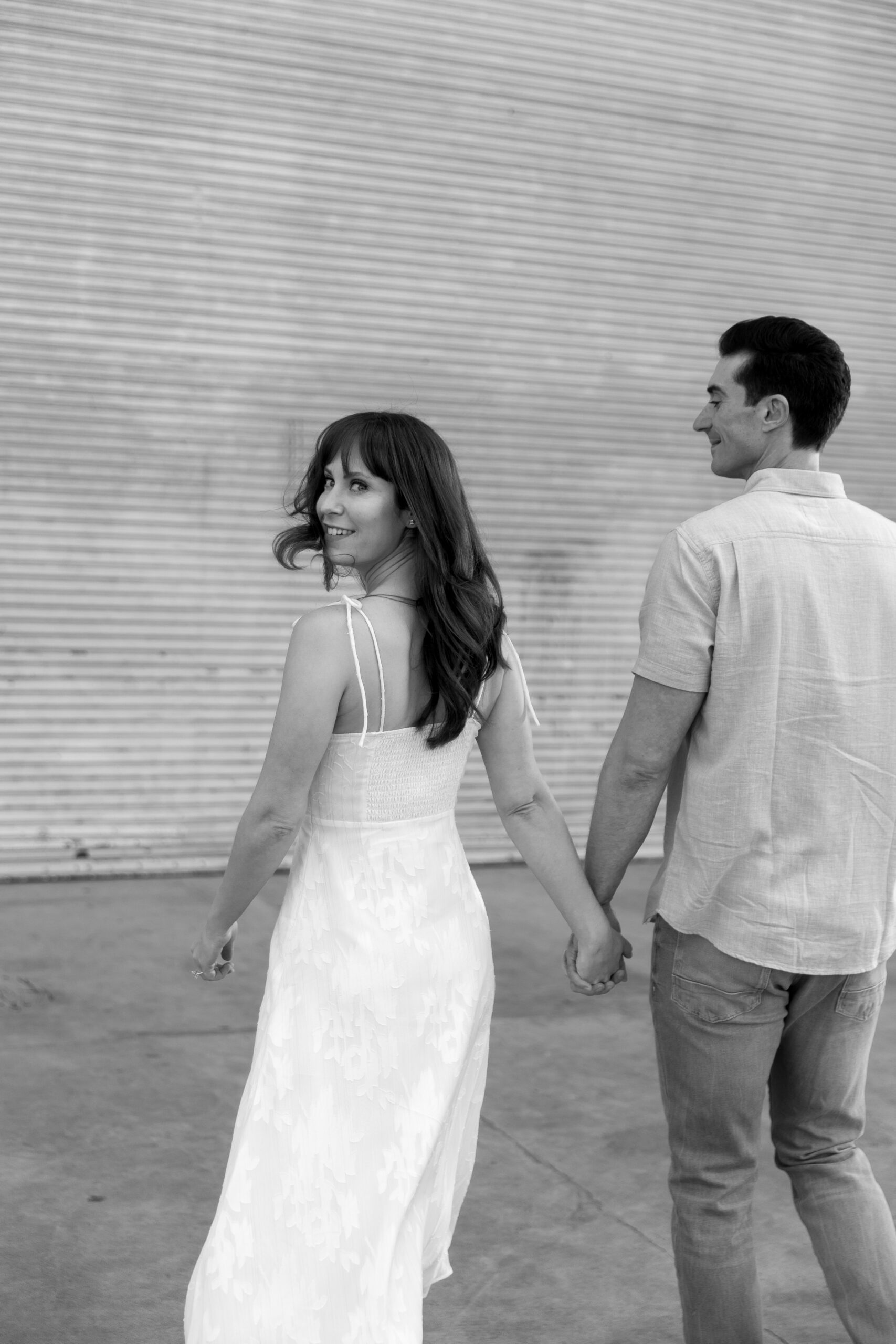 black and white photo of couple holding hands at Spreckels Organ Theater with bride looking over shoulder