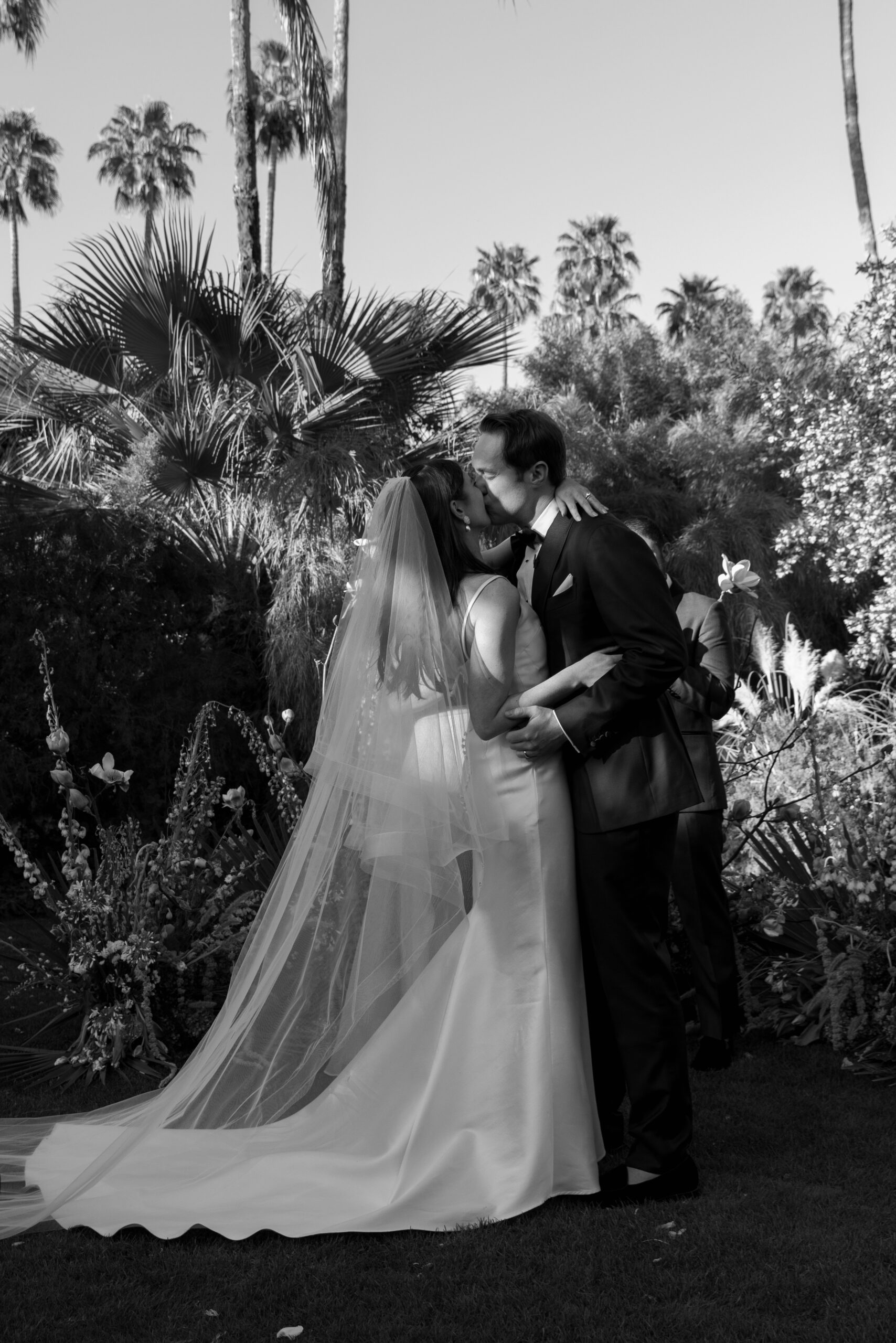 black and white photo of bride and groom first kiss at palm court at Parker