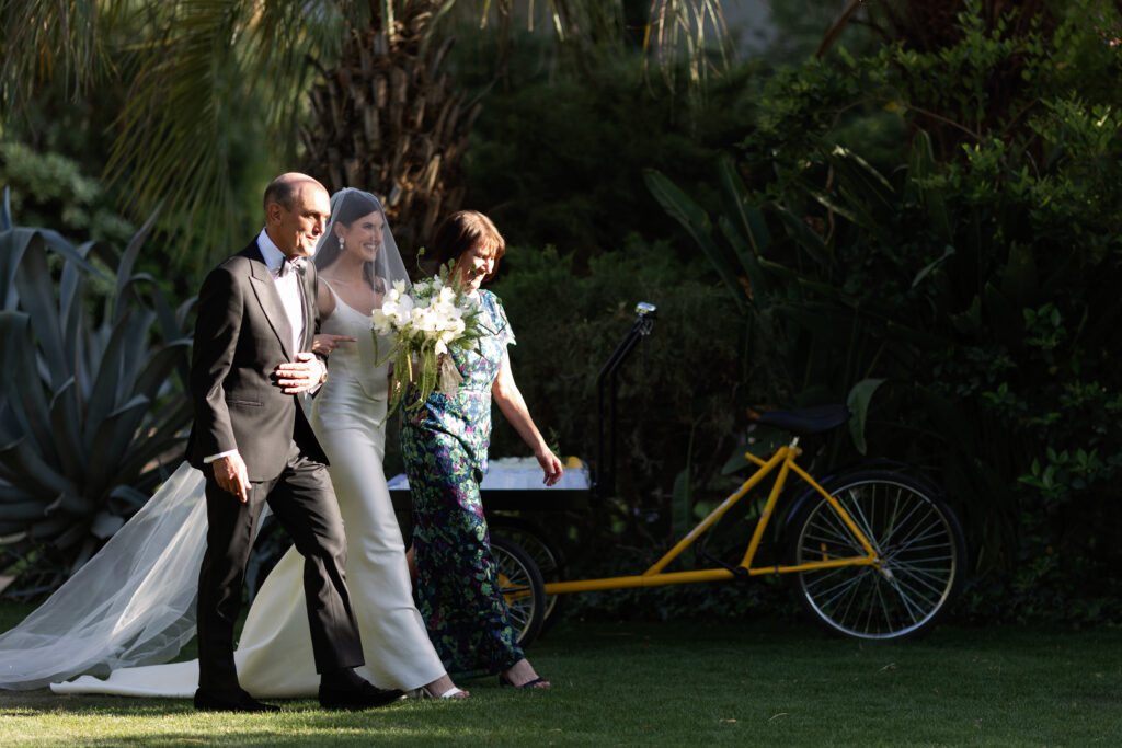 bride and parents walking by lemonade bike on way to ceremony at Parker Palm Springs