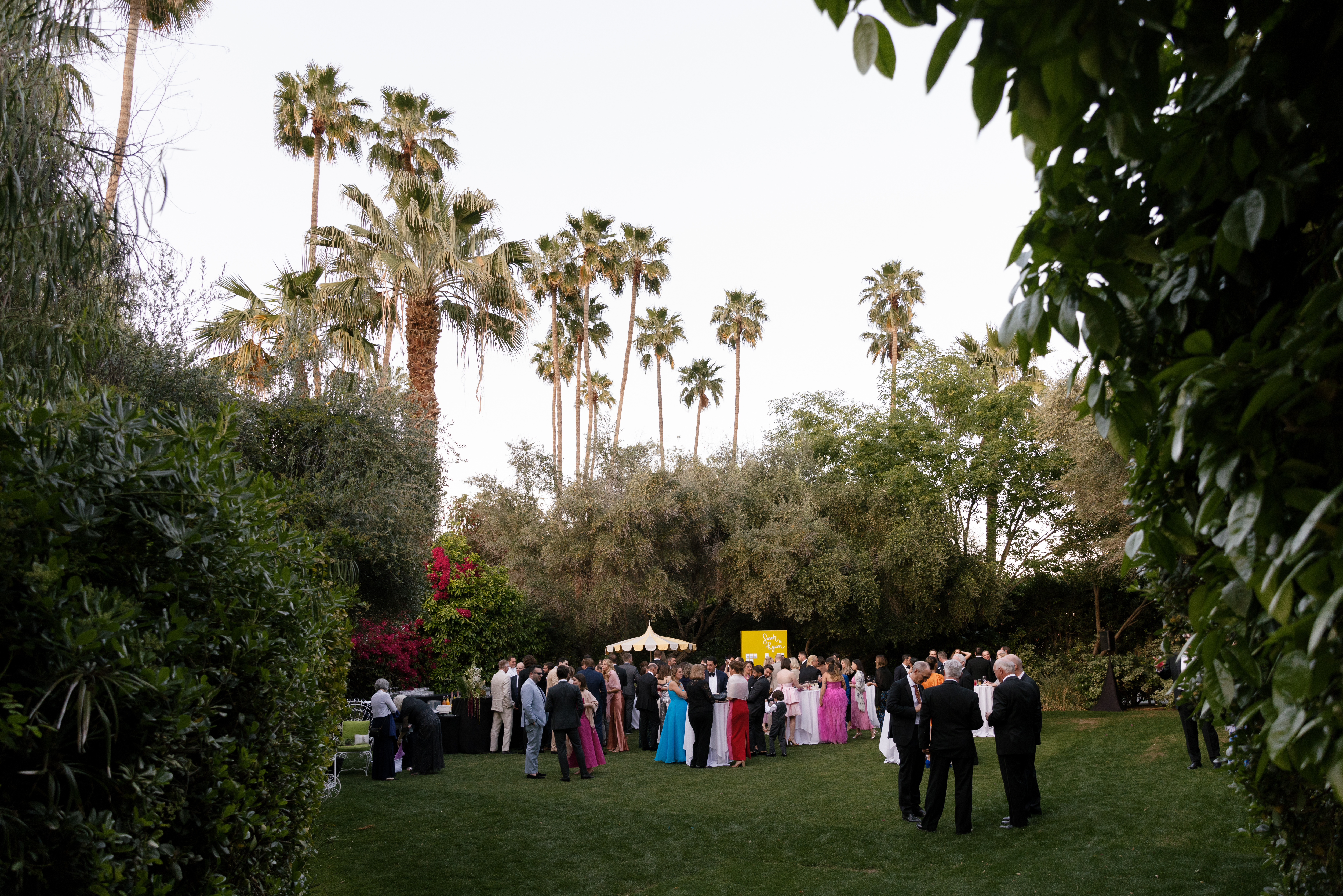 wide shot of Parker Palm Springs croquet lawn showing guests mingling during cocktail hour as the sun sets