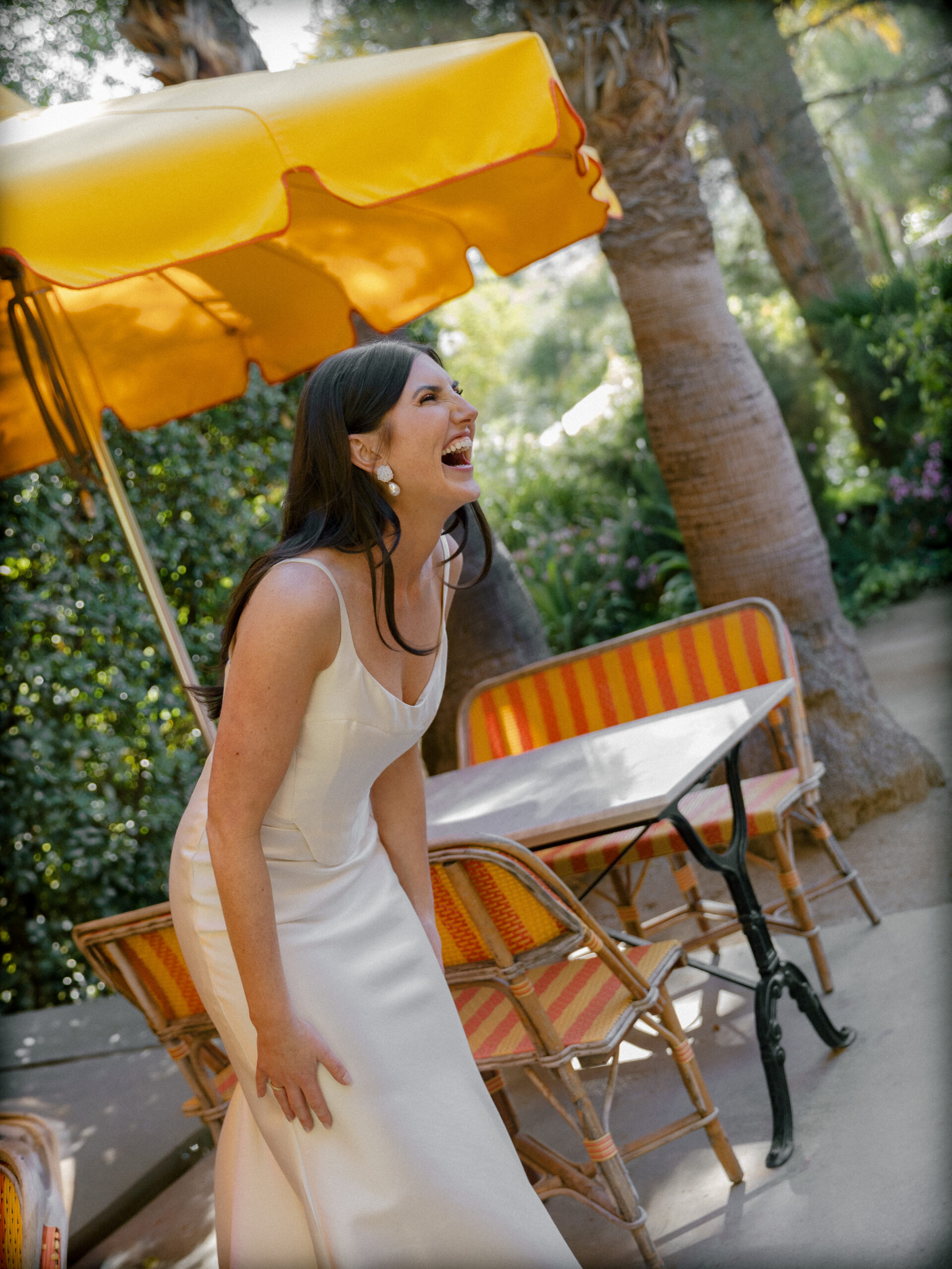 film photo of bride laughing at friend's reactions to seeing her in her dress