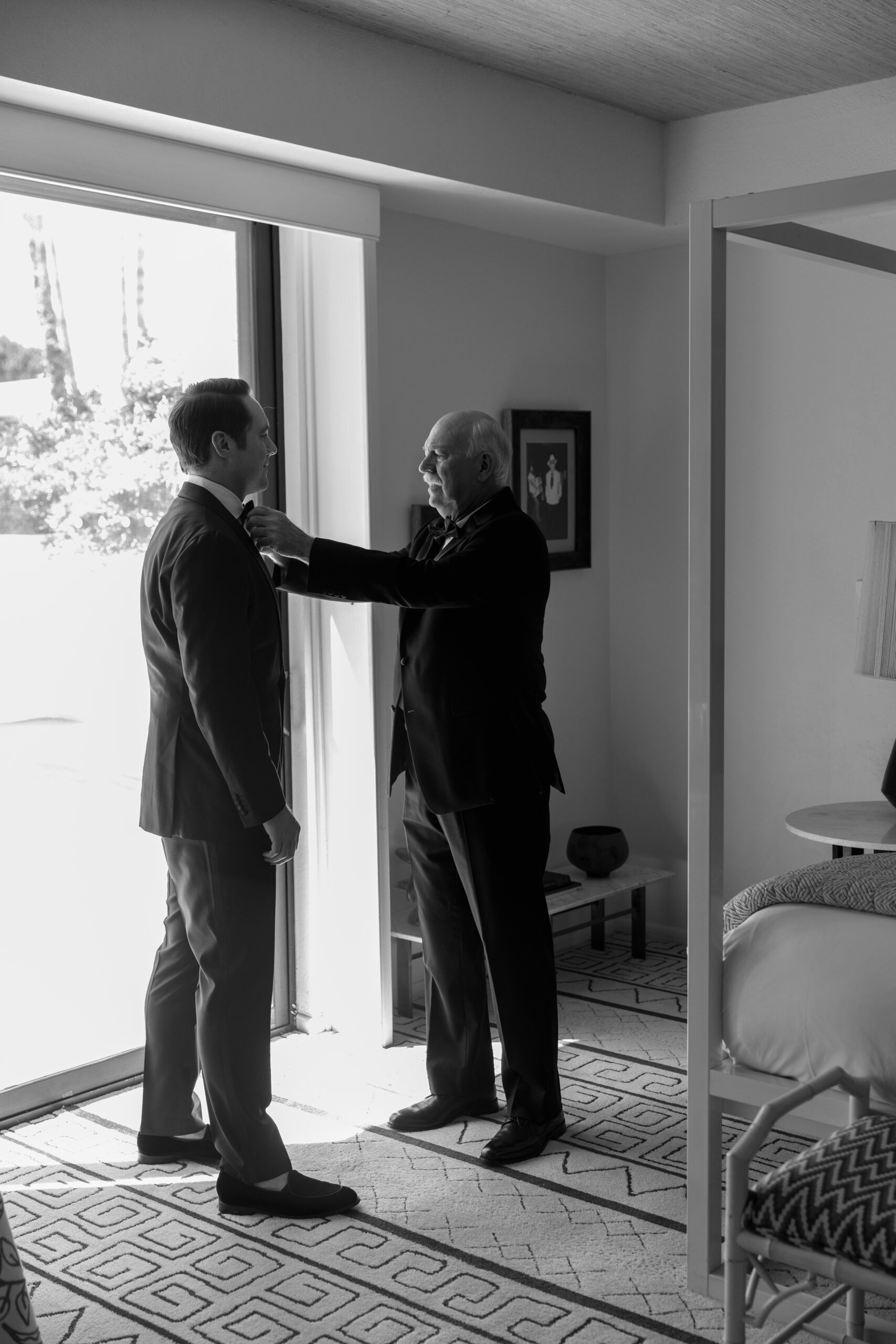 black and white photo of groom getting help with bow tie from his dad