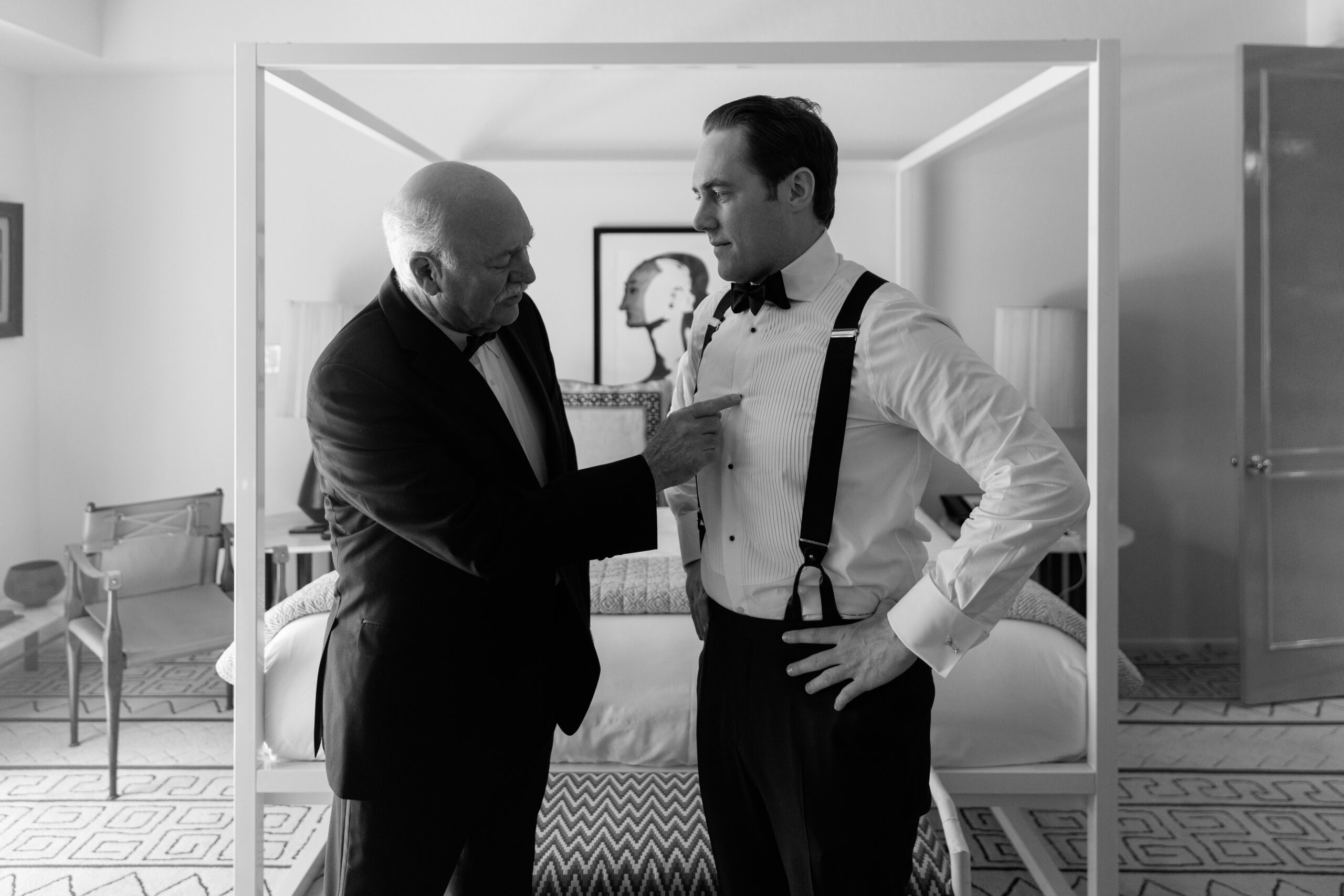 black and white photo of groom and his dad having conversation while getting ready