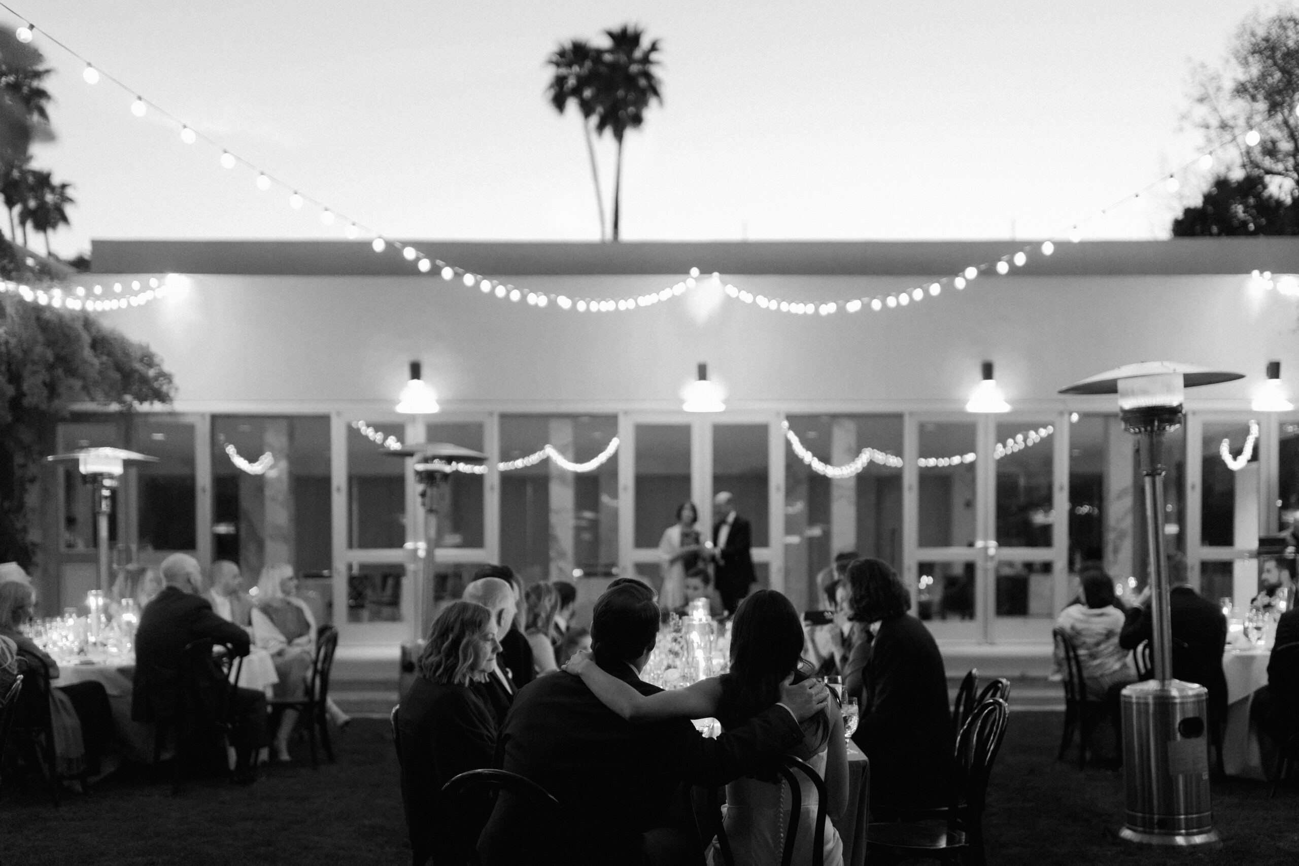 black and white wide from behind bride and groom during reception toasts on banquet lawn at Parker Palm Springs