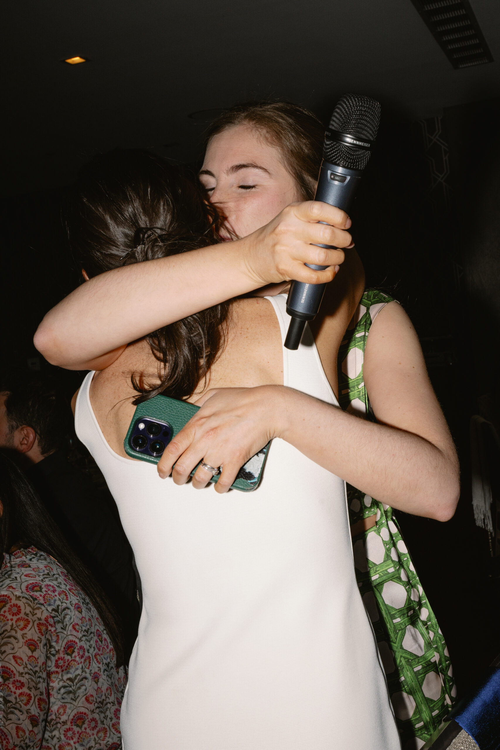 flash photo of bride embracing maid of honor during rehearsal dinner toast