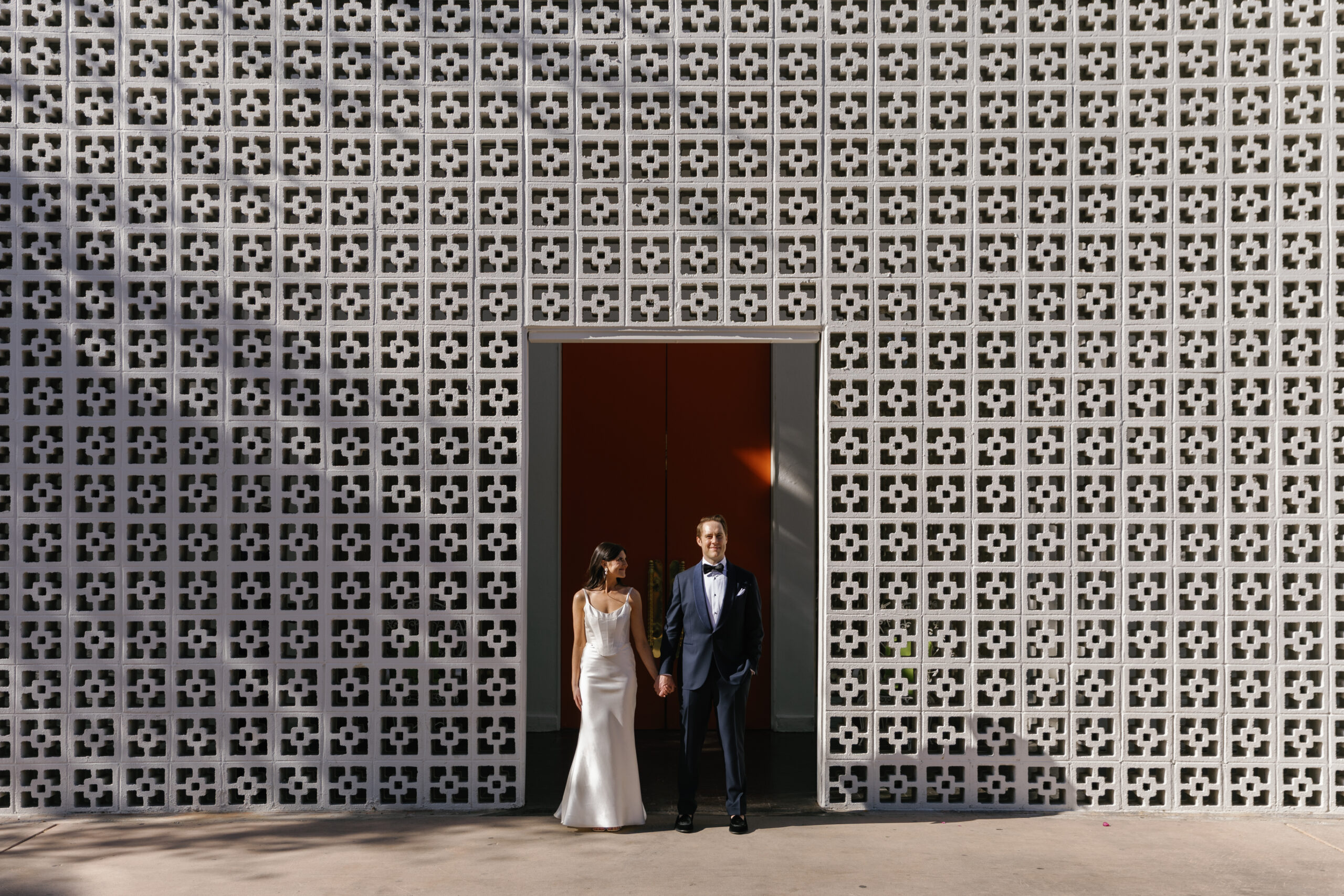 wide shot of bride and groom posing in front of parker palm springs entrance