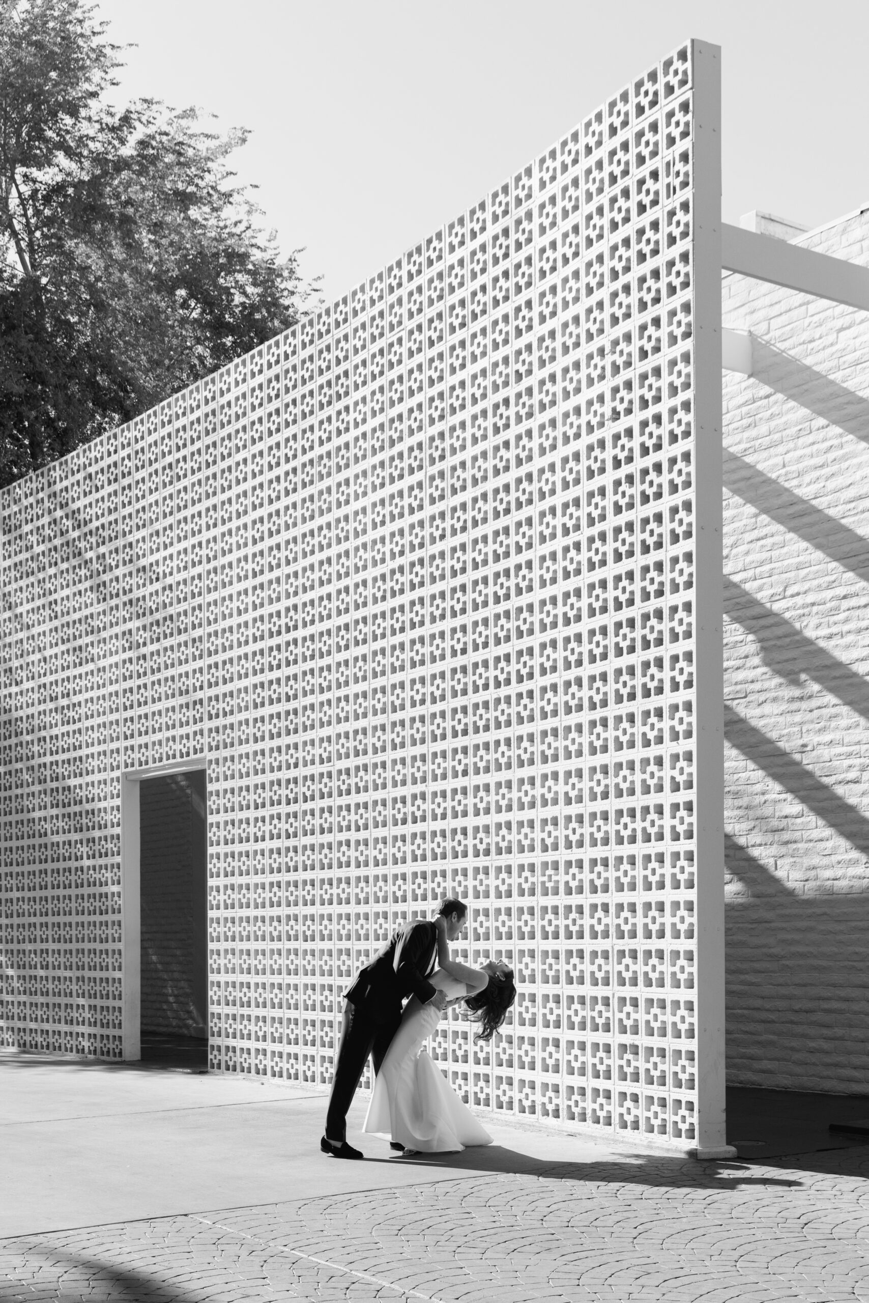 black and wide profile shot of groom dipping bride outside Parker Palm Springs entrance