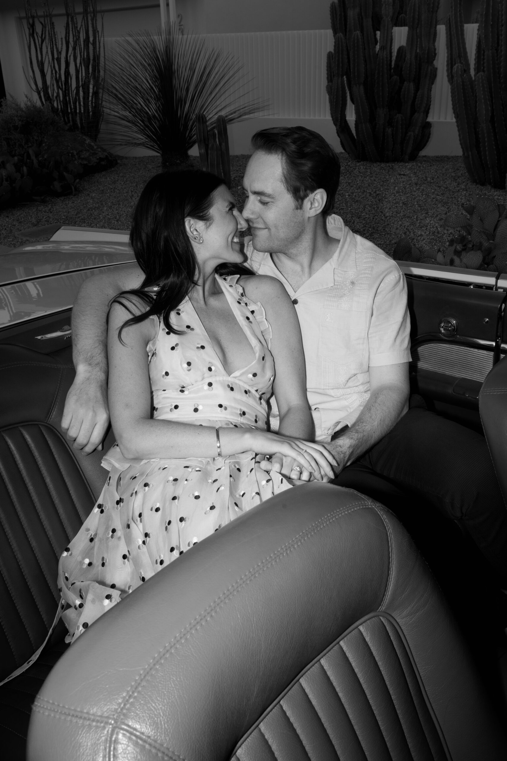 black and white flash photo of couple kissing in backseat of vintage convertible